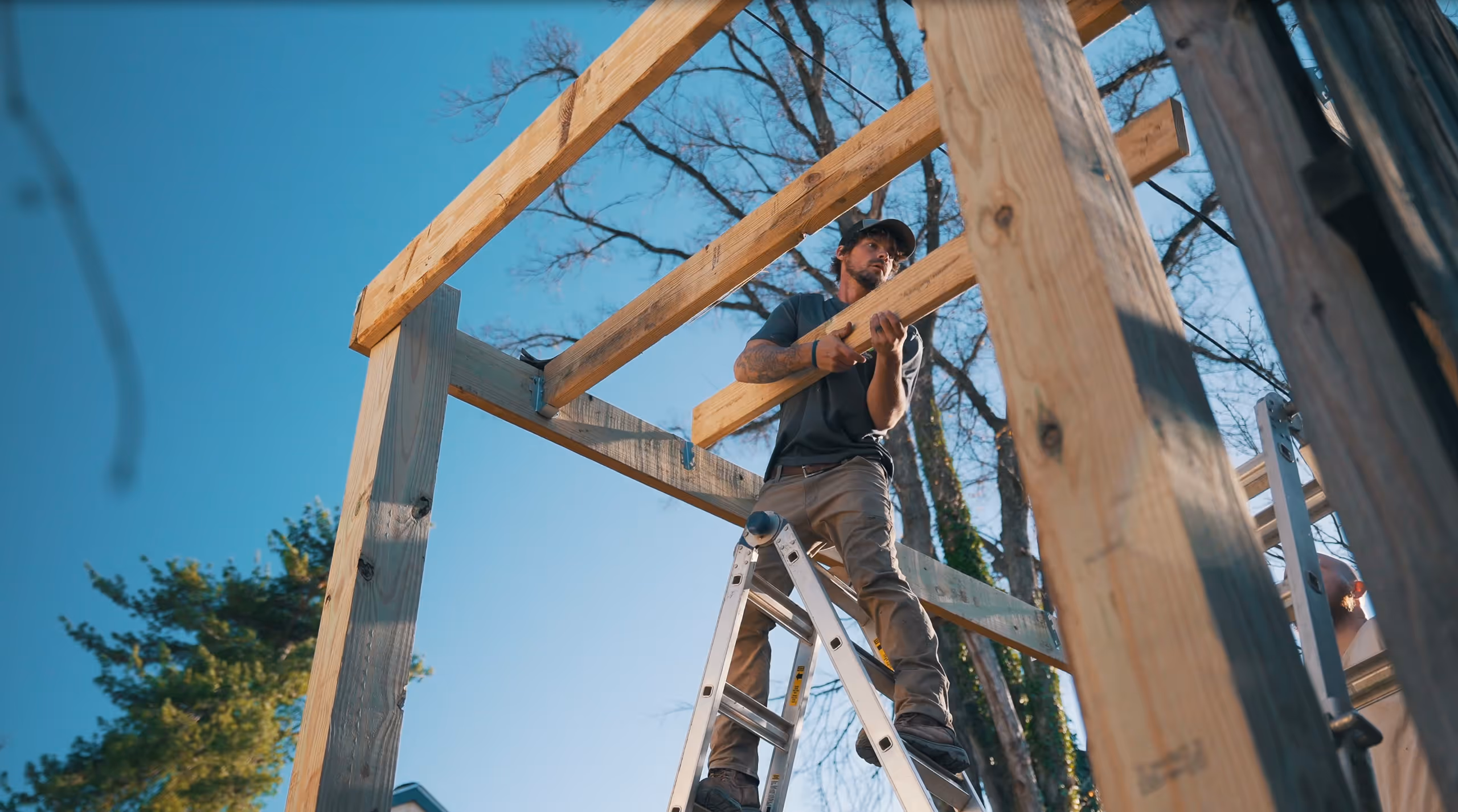 A man holding a beam standing on a ladder 
