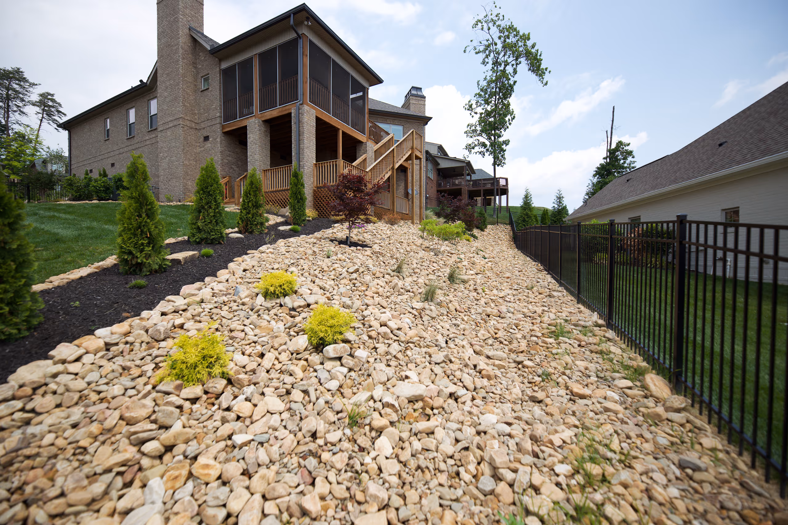 A luxury home with a landscaped hillside and a stone retaining wall