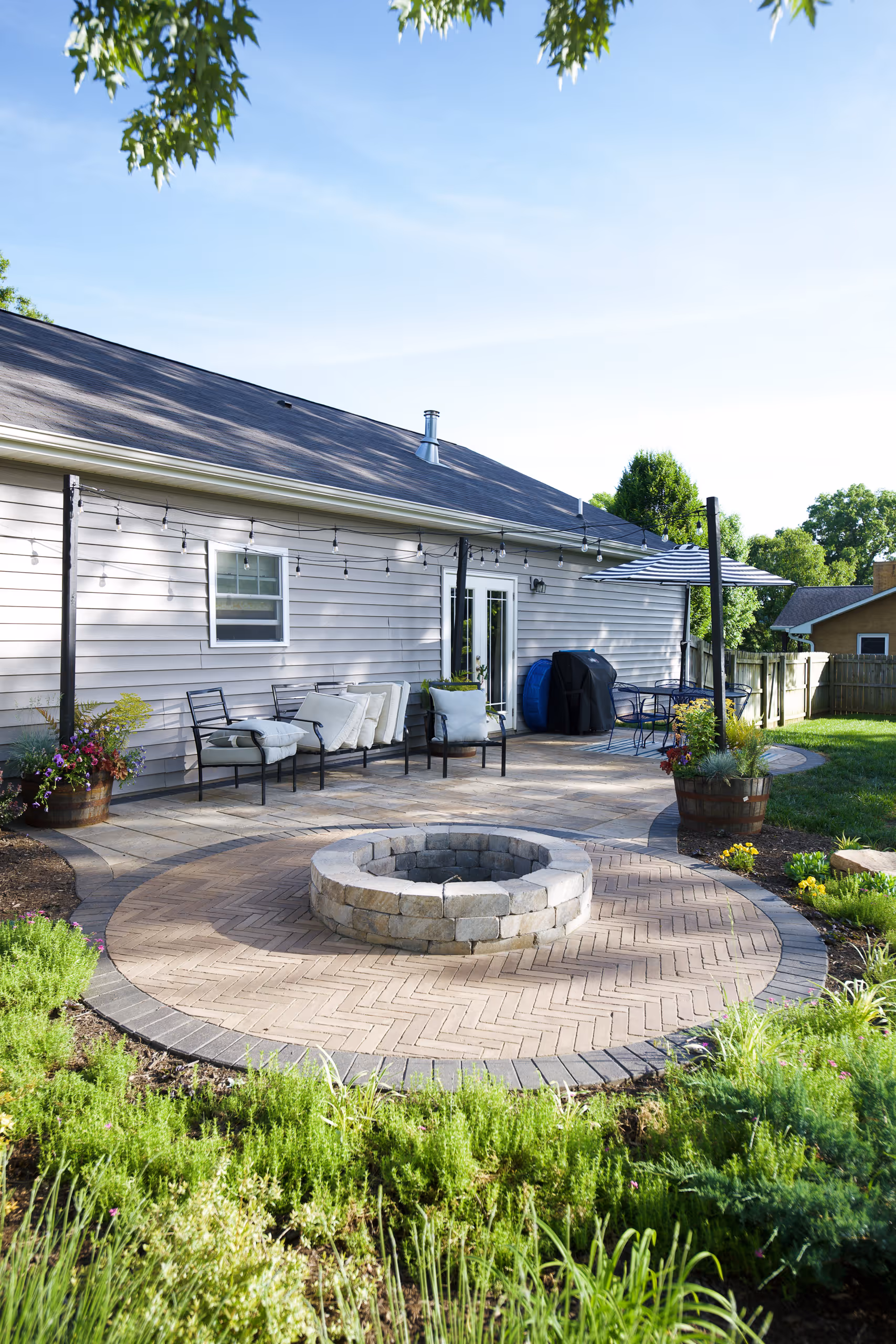 Backyard patio with a fire pit, seating area, and string lights