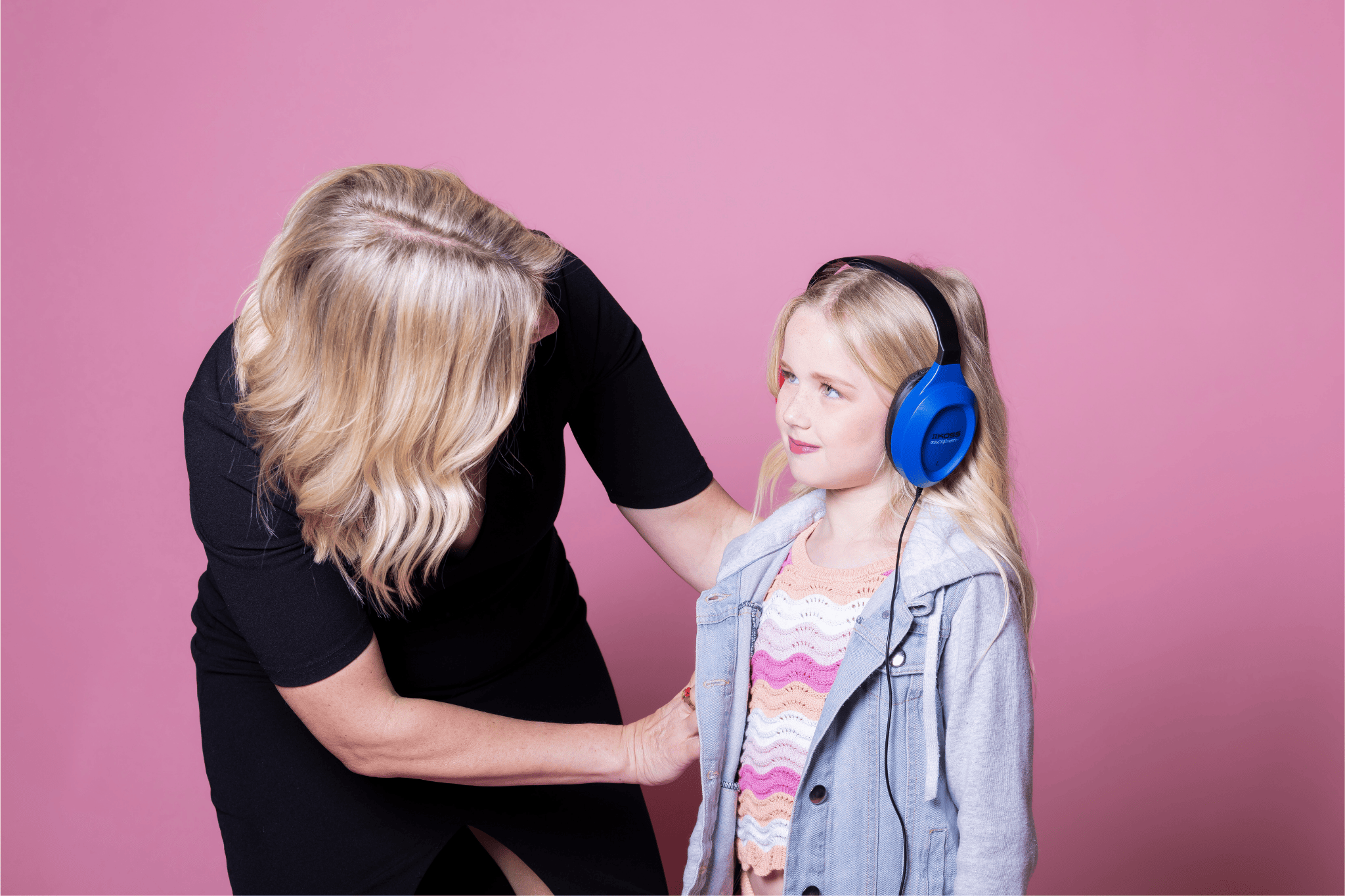 An audiologist gently places noise-canceling headphones on a young girl during a hearing evaluation for auditory processing disorder.