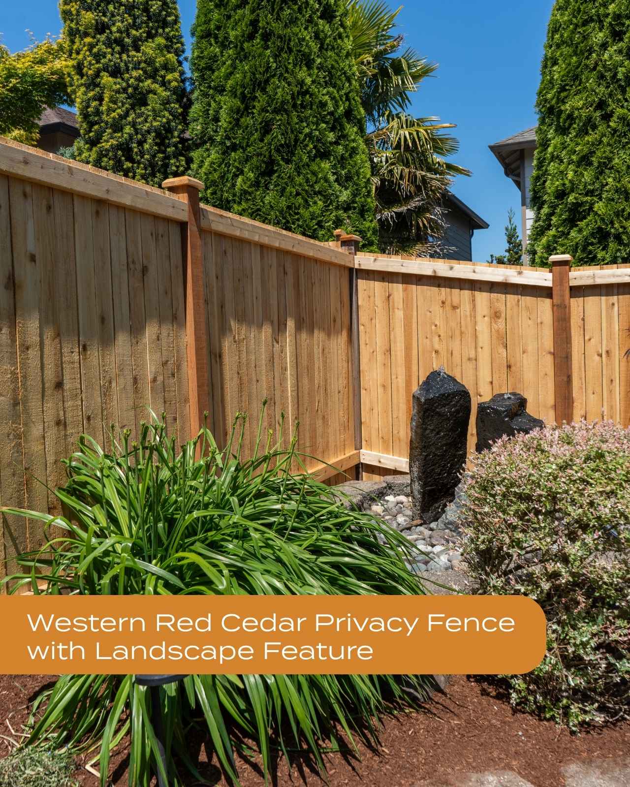 L-shaped Western Red Cedar privacy fence enclosing a landscaped backyard with decorative rock water feature and lush greenery