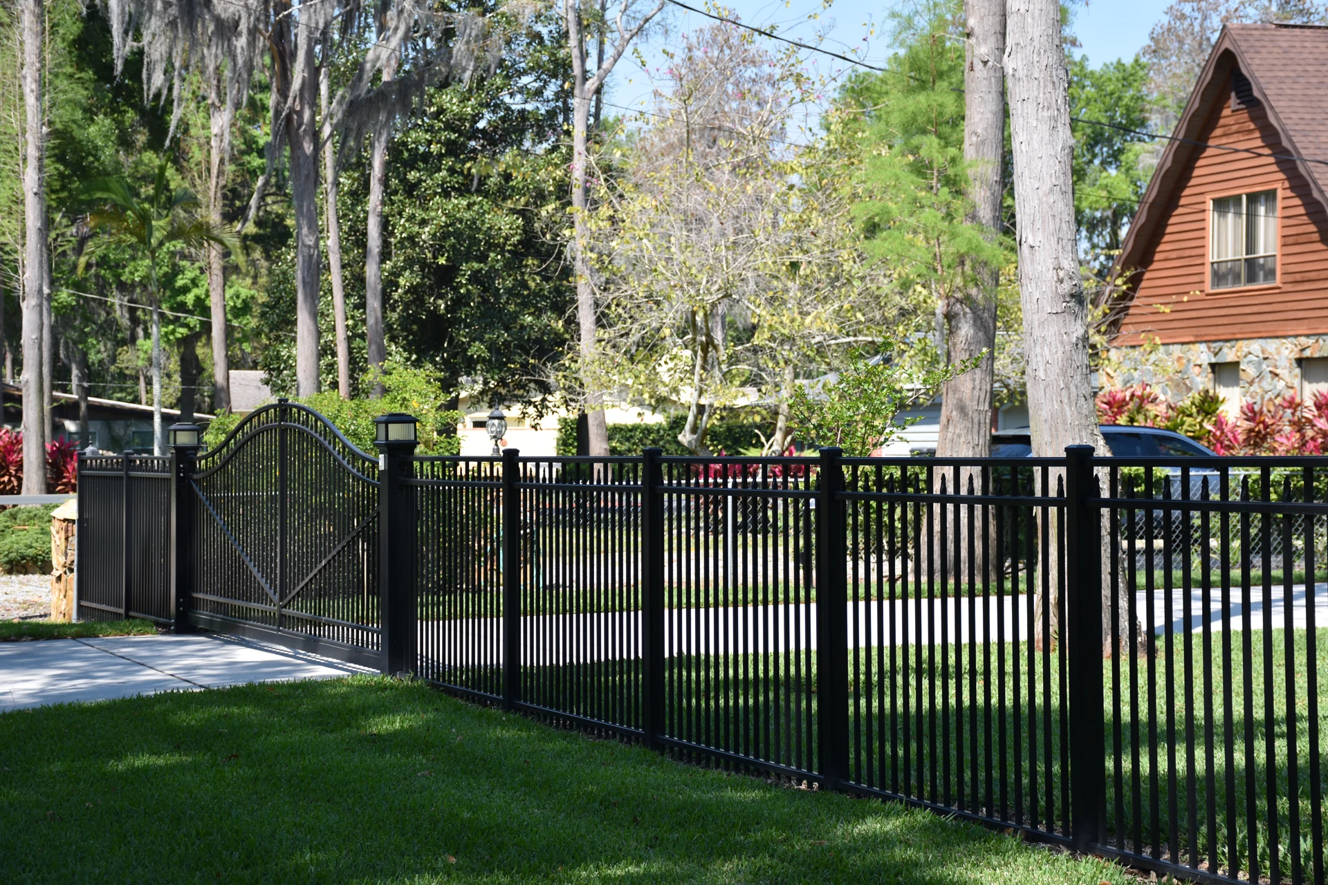 Black aluminum fence with arched walk gate installed in a residential front yard