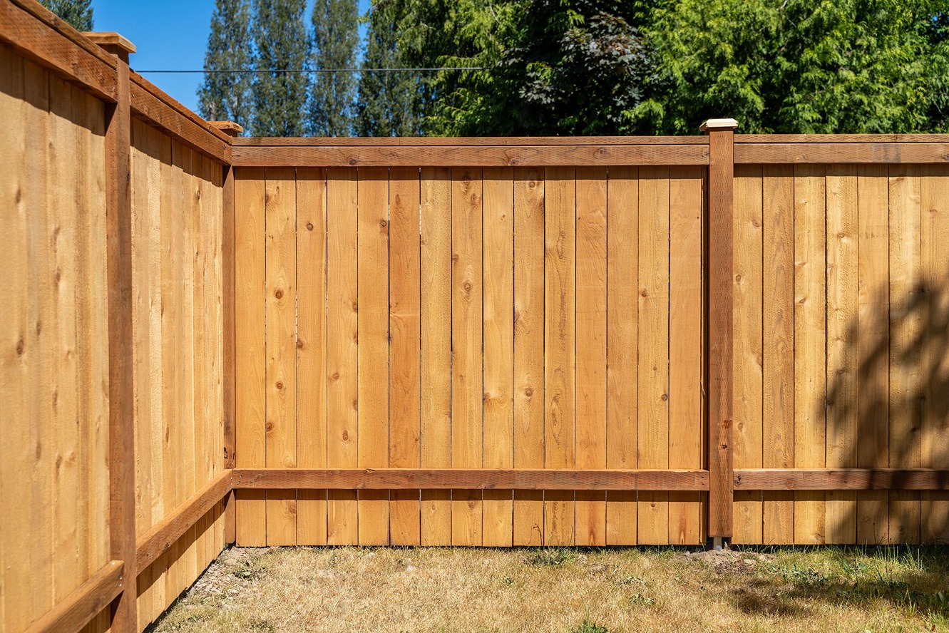newly installed wooden privacy fence constructed with vertical cedar planks and horizontal support beams