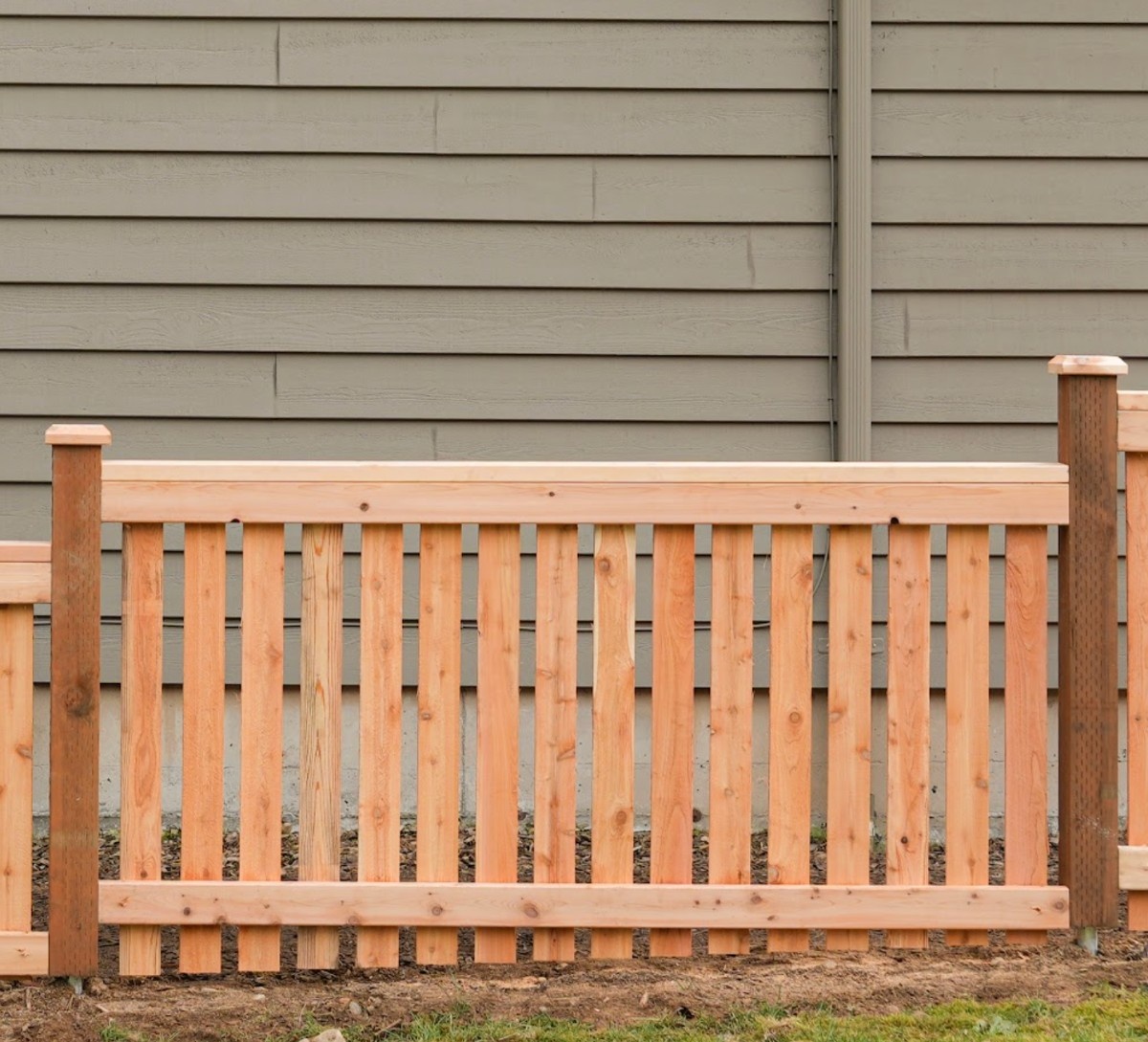 Newly installed cedar picket fence installed next to a two-storey Seattle home