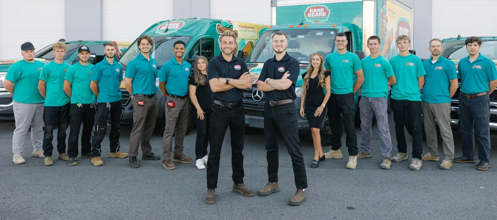 Two Rare Bears Fencing owners standing in front of their full team beside branded service vans and box truck