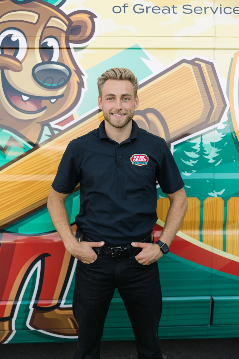 Rare Bears Fencing co-owner smiling in front of a branded service van with the bear mascot wrap