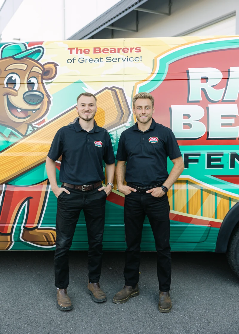 Rare Bears Fencing co-owners standing together beside a branded van with the company bear mascot wrap