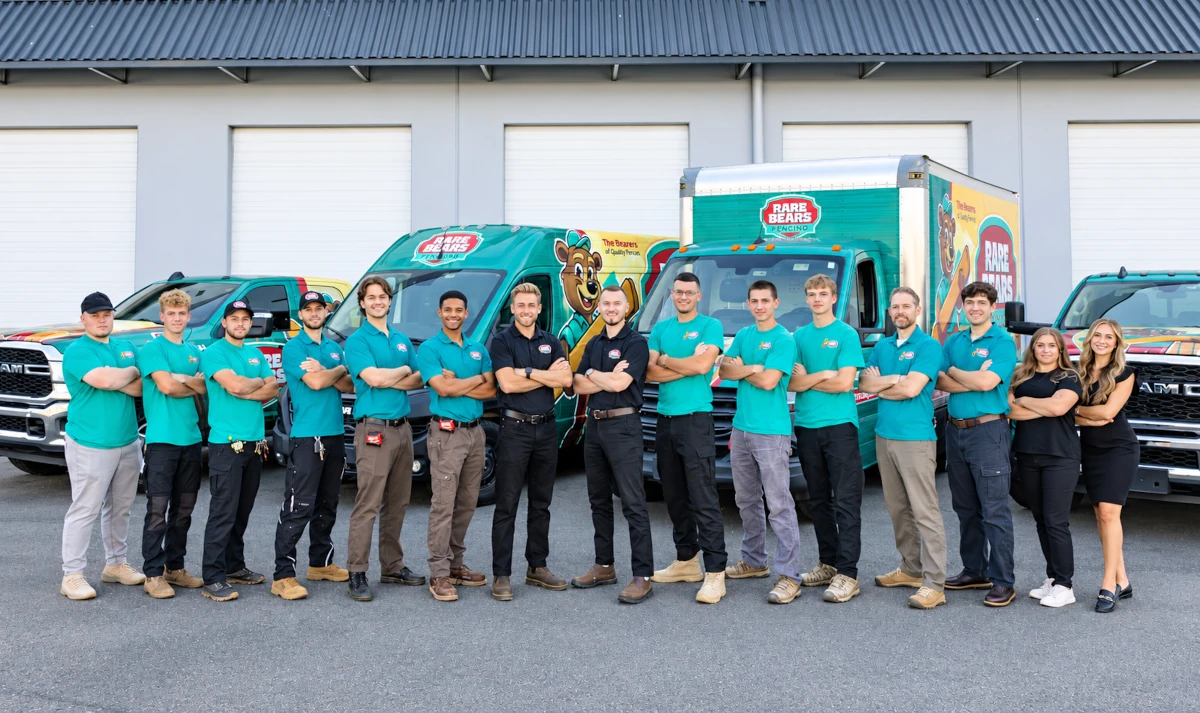 Rare Bears Fencing team standing in a line with arms crossed in front of branded teal service vans and box truck outside the company warehouse