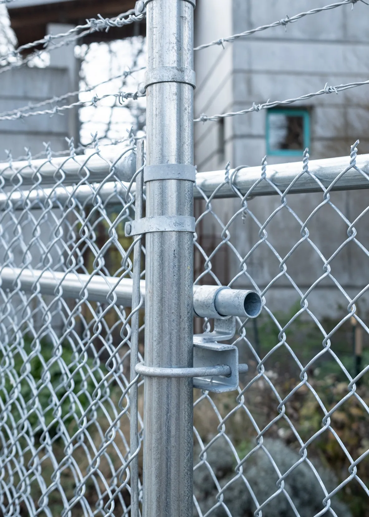 Security chain link fence with concrete-set posts and taut diamond mesh protecting a business perimeter