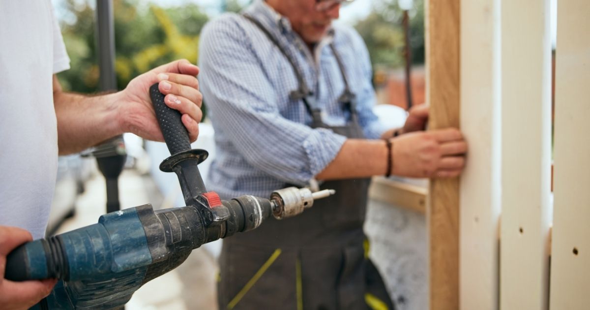 two workers installing wooden fence