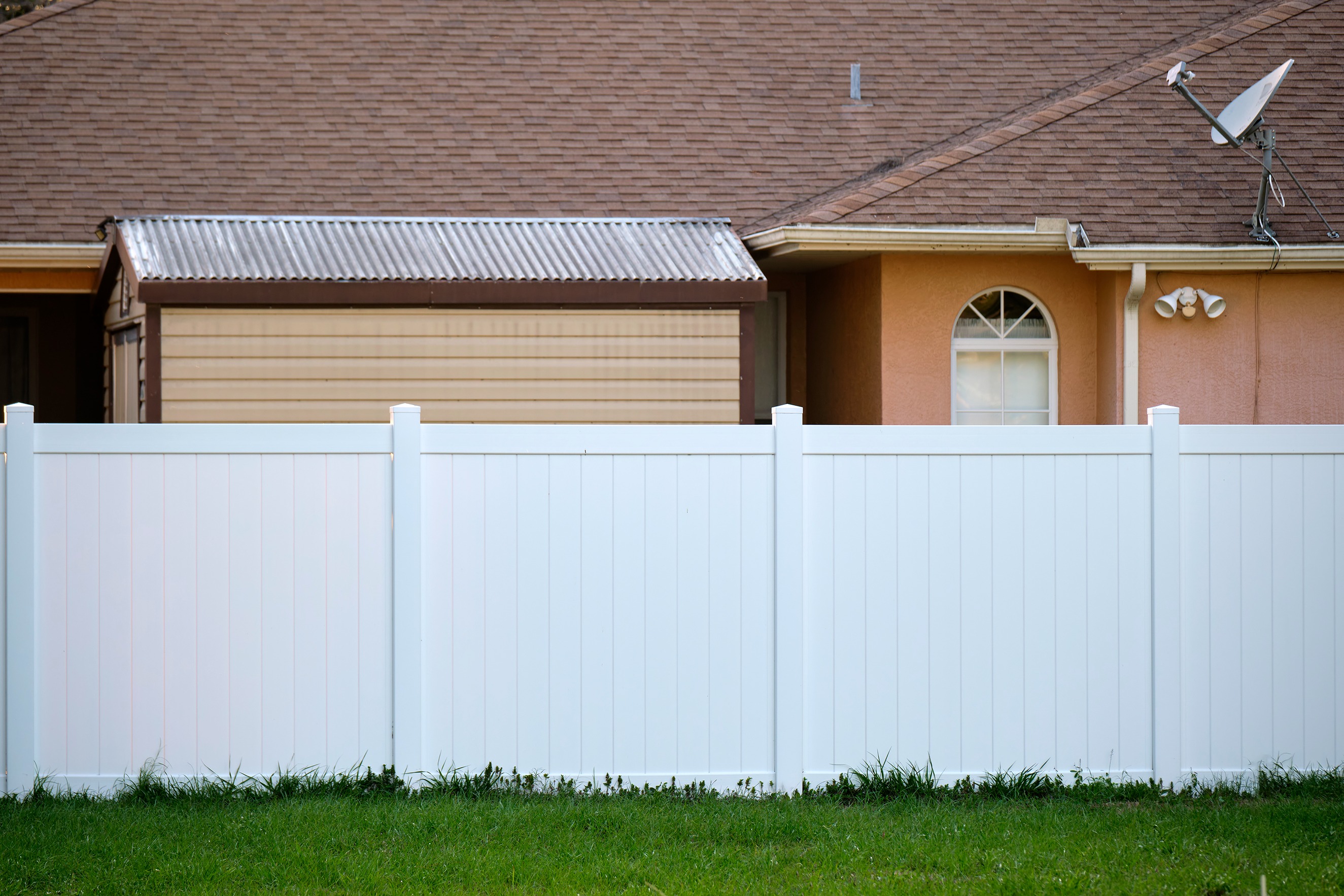 Vinyl fence installed in a residential backyard with clean panel design