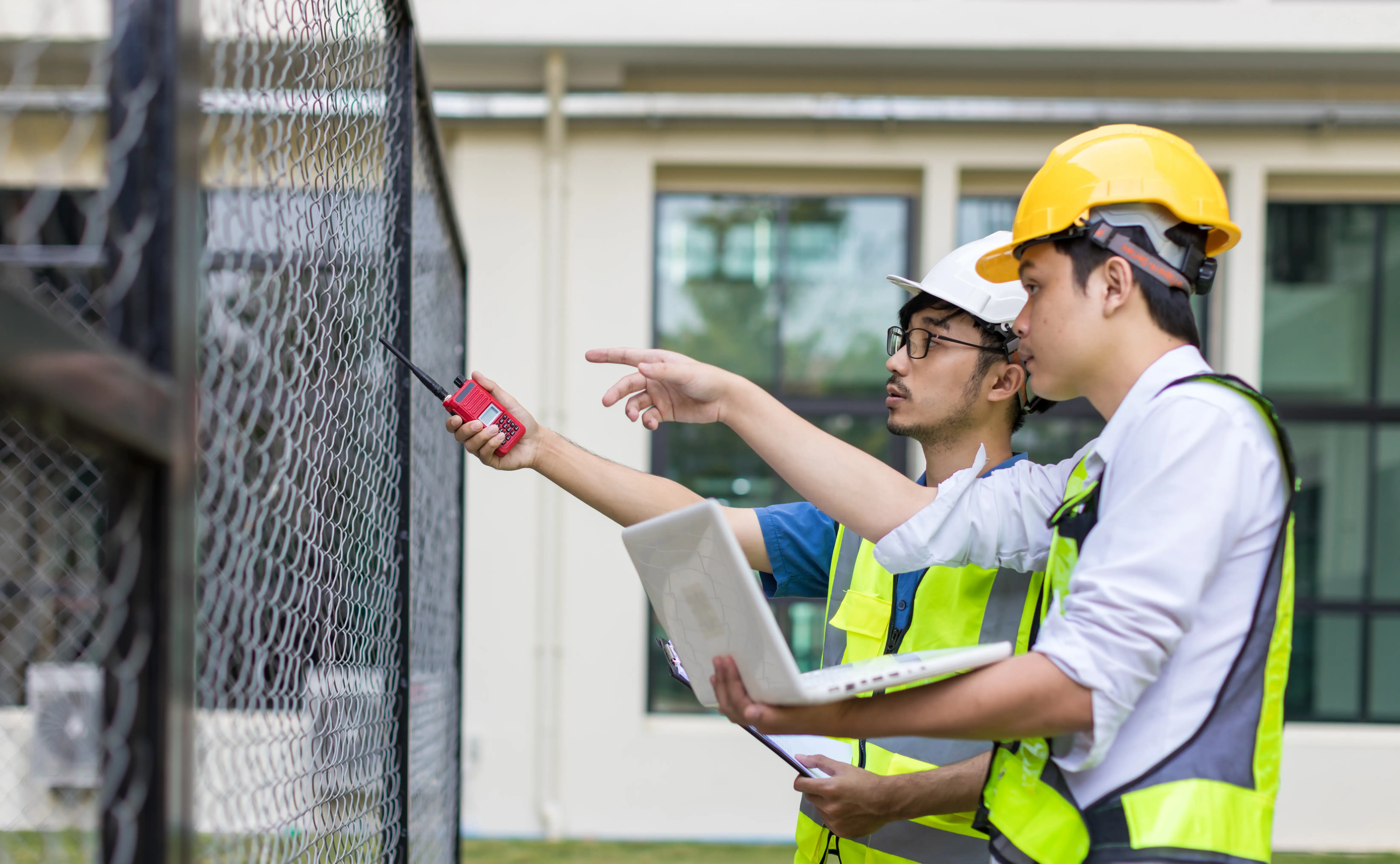 Two Seattle fence contractors inspecting a commercial chain link fence installation