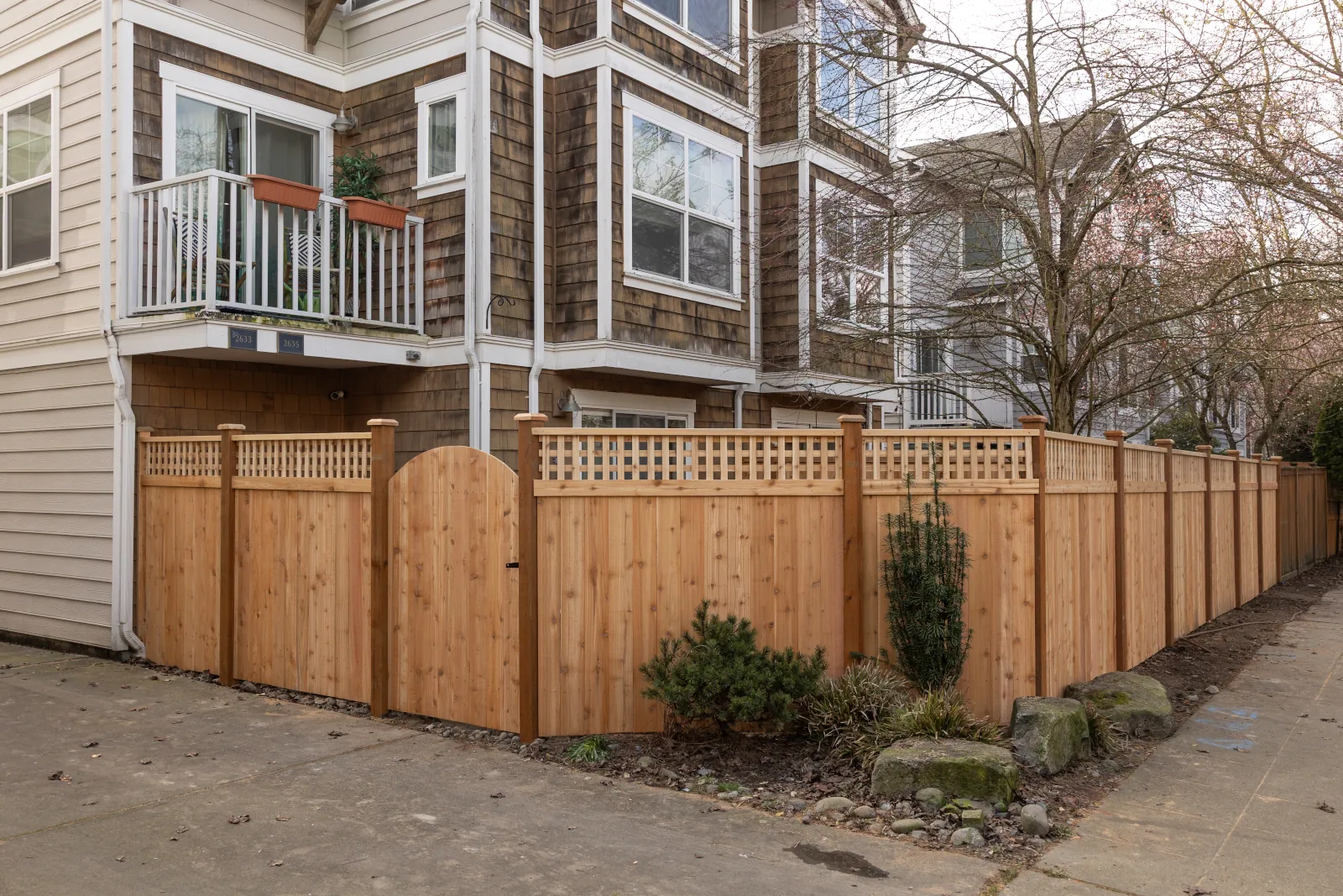 New cedar fence with square lattice top and arched gate wrapping a townhome yard