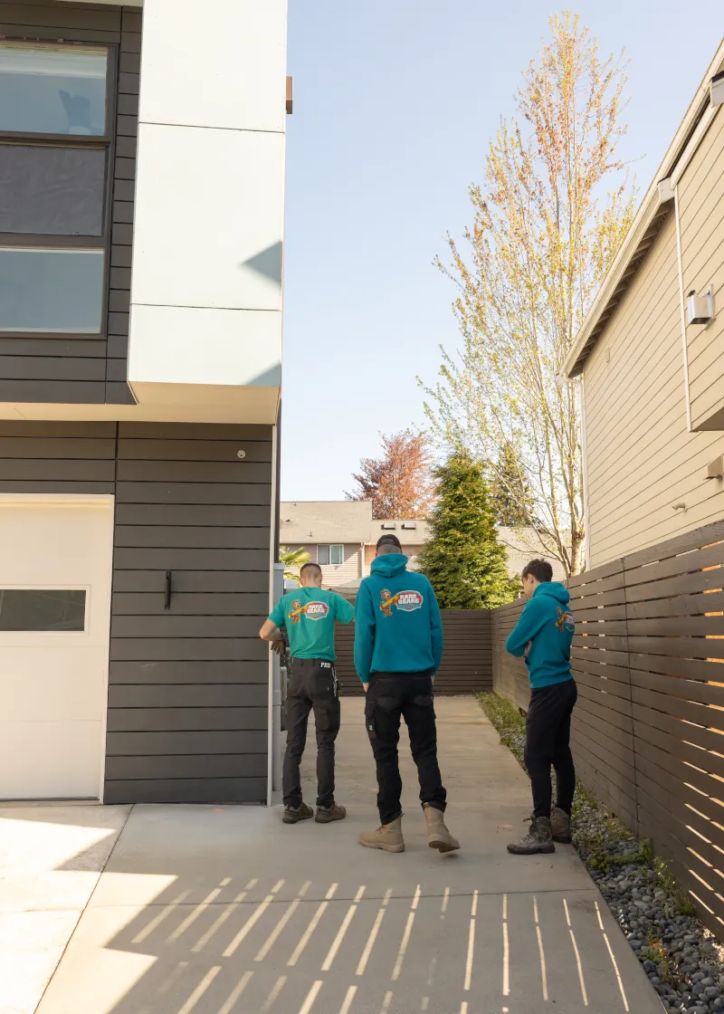 Fence crew assessing an open side yard between two modern homes before installing a horizontal cedar gate