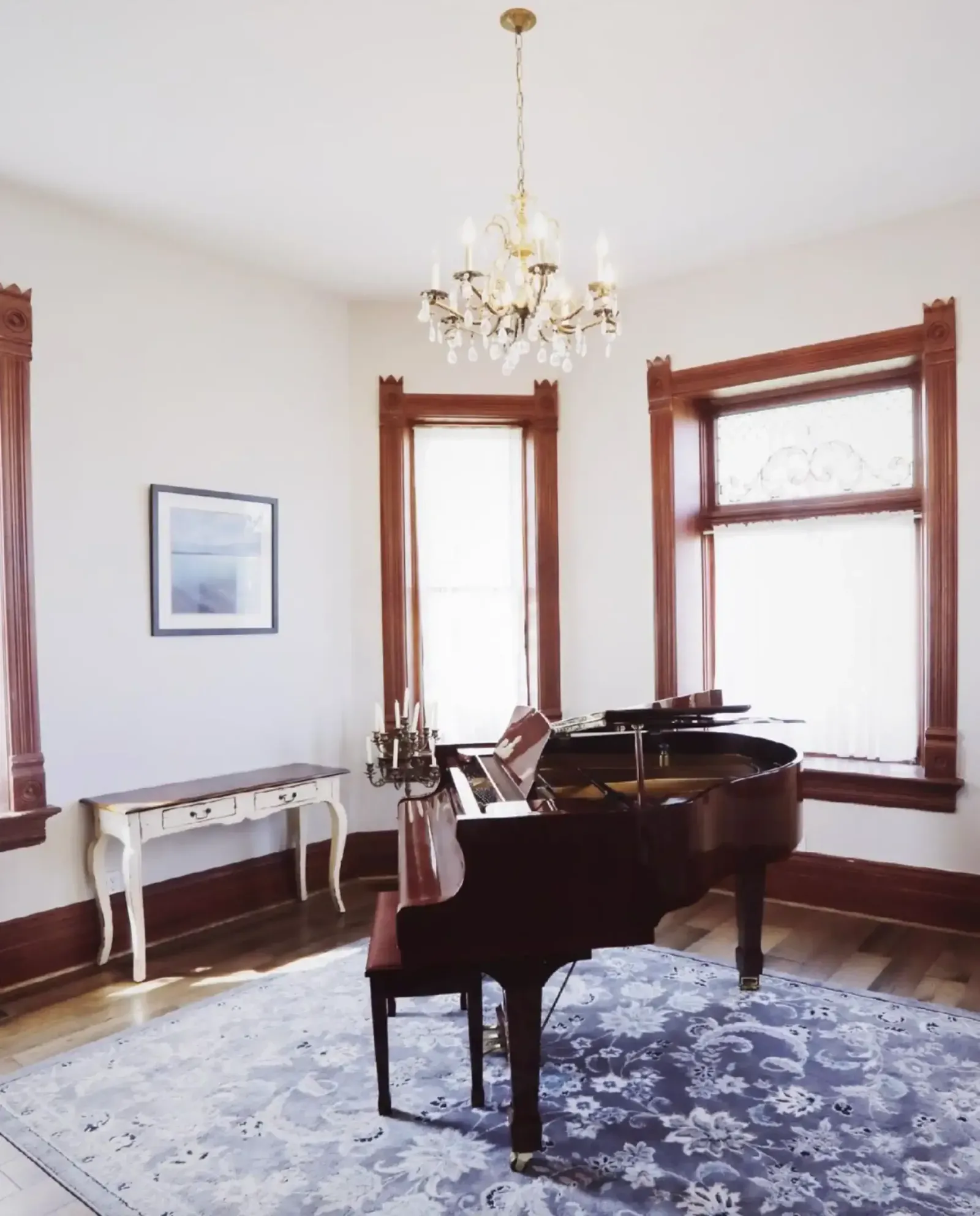 Grand piano under a chandelier in the restored house