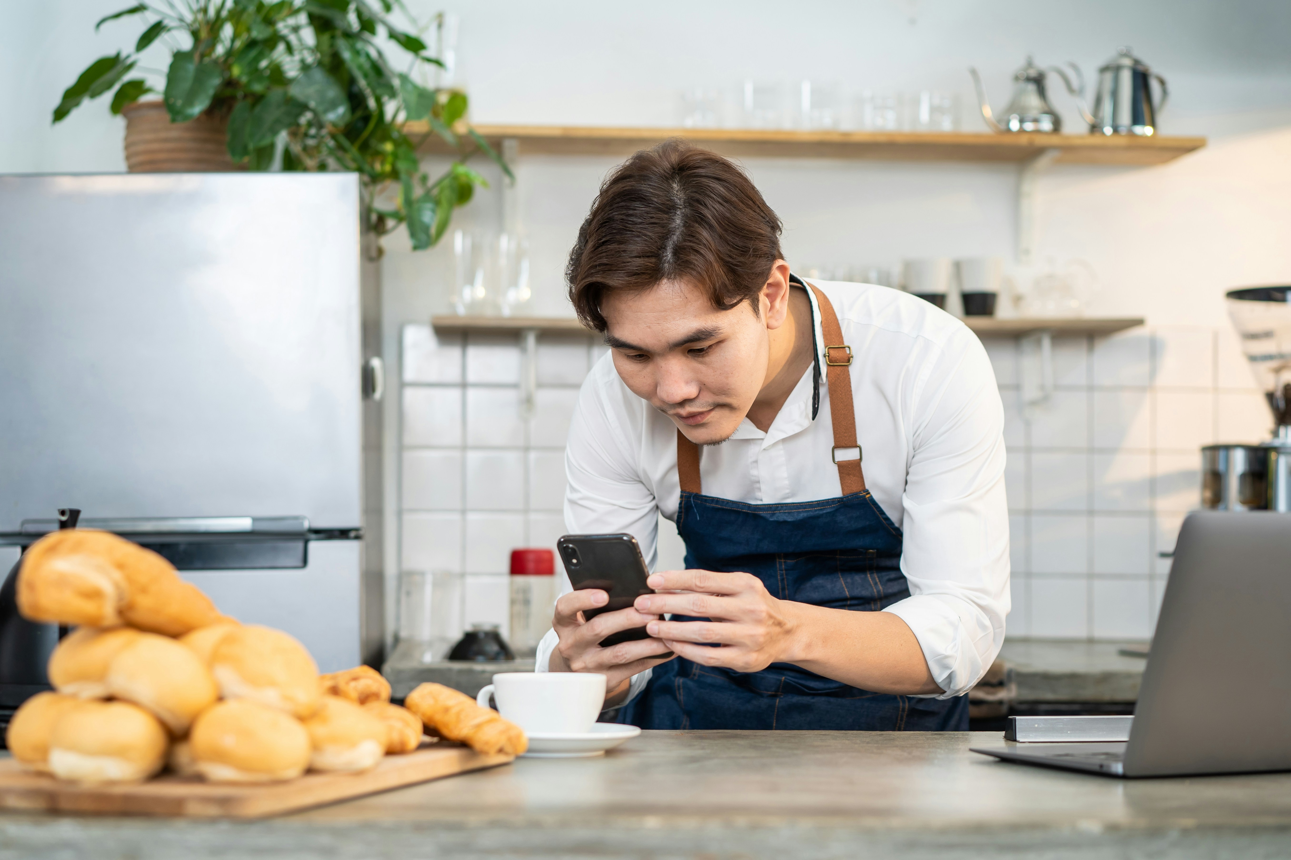 Frontline worker in a red jacket and cap using a mobile phone, showing the importance of mobile-first communication and real-time feedback for deskless employees.