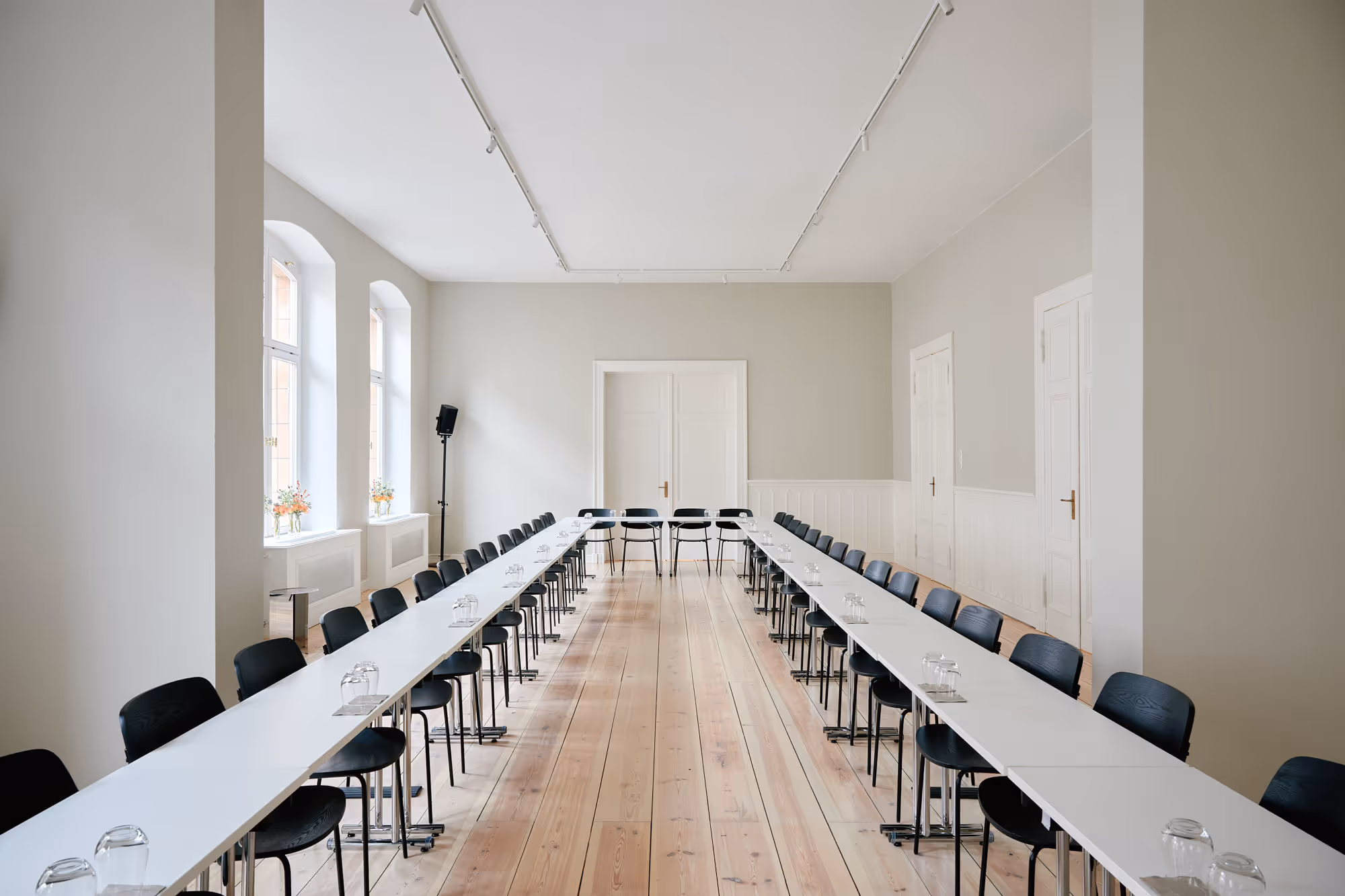 Seminarraum in Berlin Mitte mit weißen Tischen in U-Form gestellt und schwarzen Stühlen