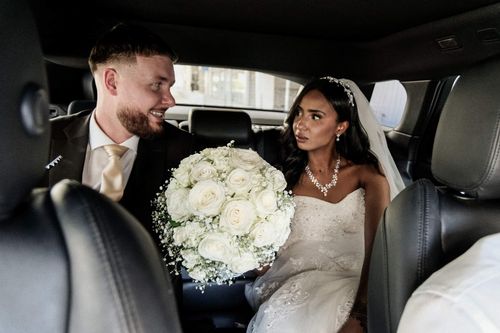 Photographie de mariage : les mariés échangent un regard complice dans la voiture
