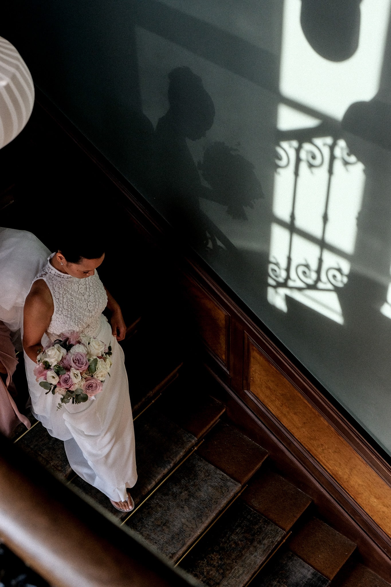 Reportage de mariage à Lyon – la mariée descend l’escalier dans un jeu d’ombres poétique