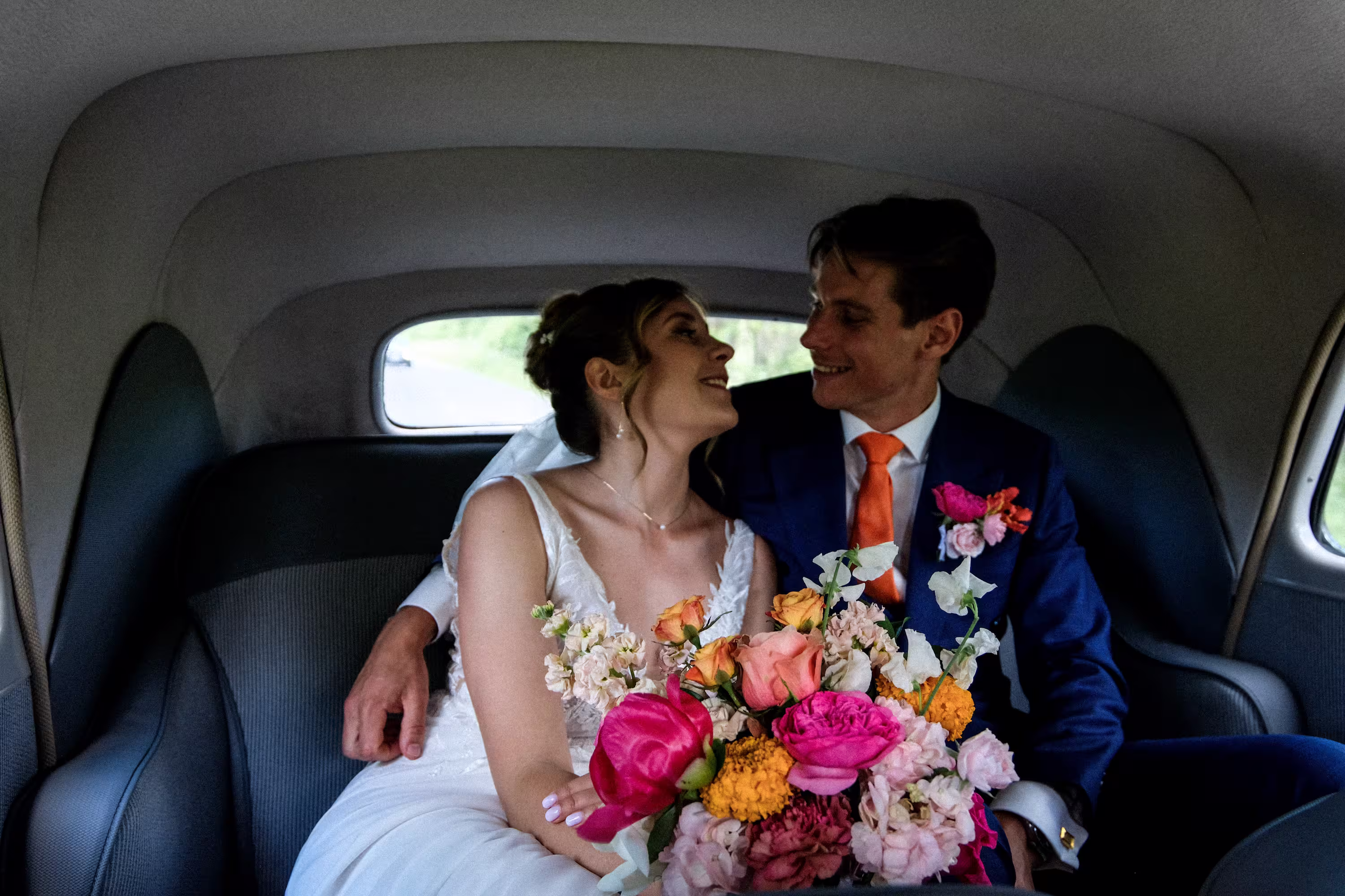 Photographie de mariage en voiture vintage à Lyon, bouquet de fleurs vives en premier plan