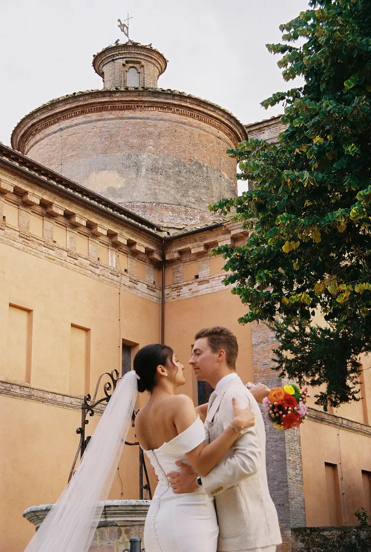 Couple de mariés devant une église historique lors d’un mariage au Podere Incrociati, en Toscane.