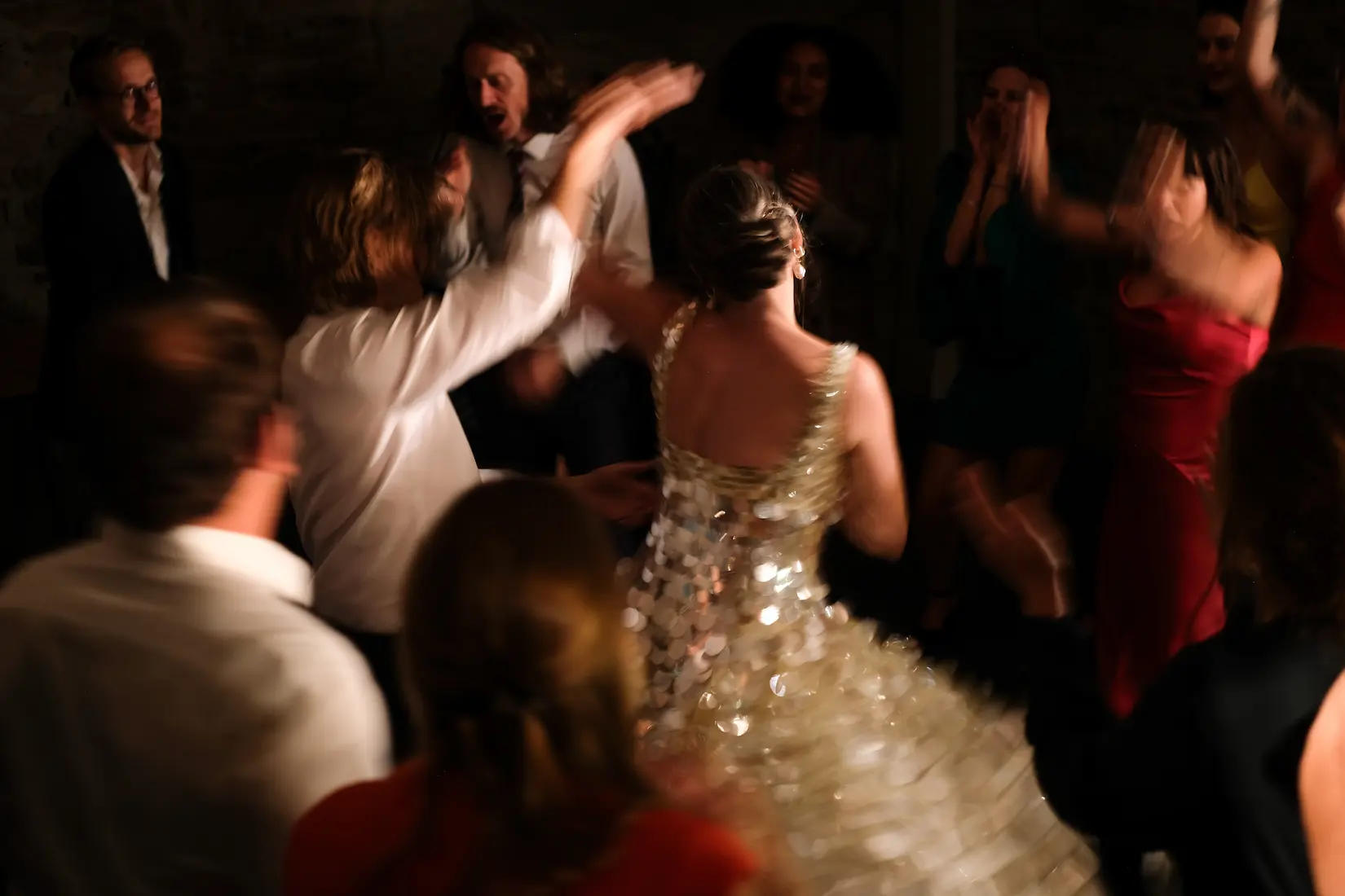 Invités dansant autour de la mariée en robe scintillante pendant la soirée de mariage.