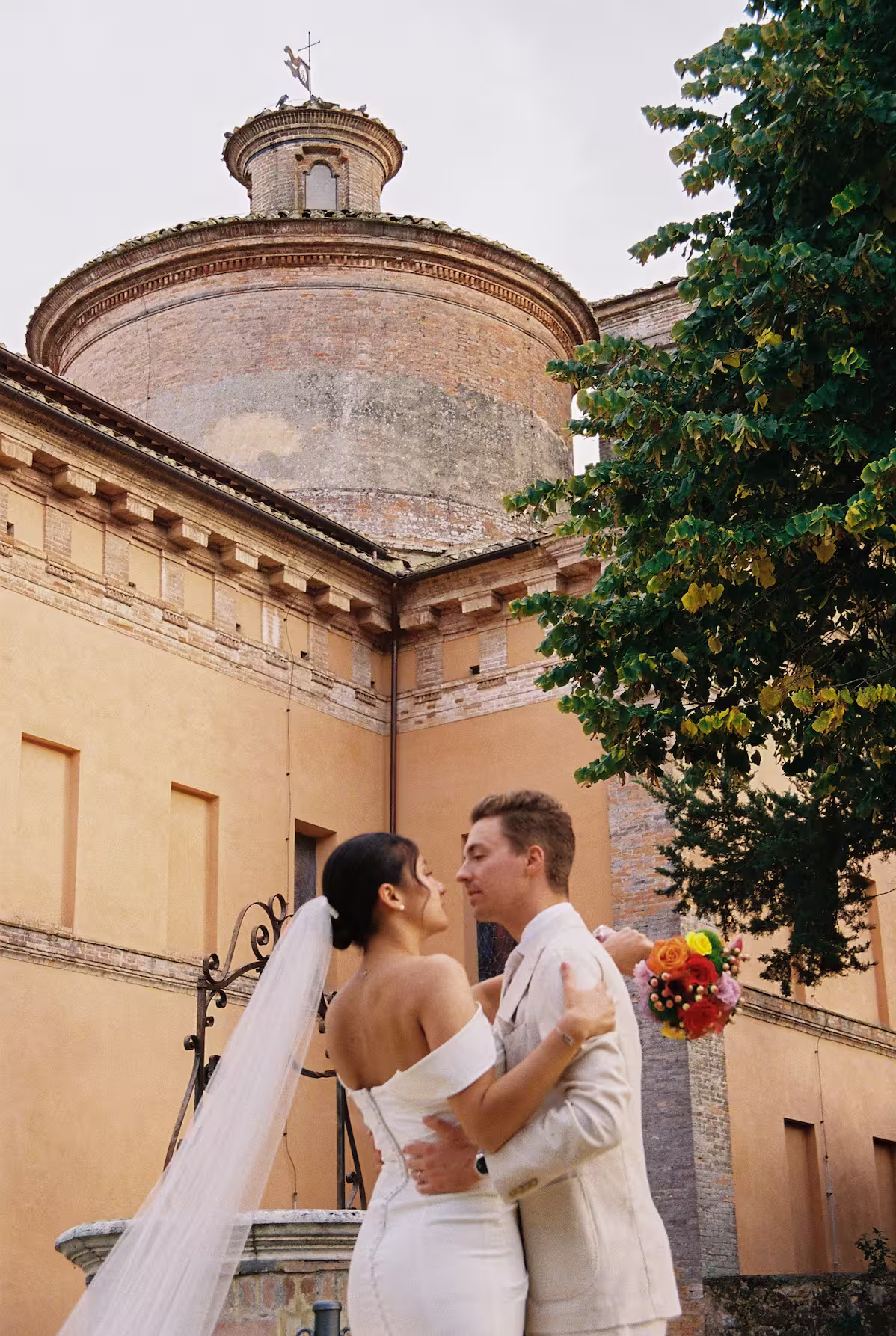 Couple de mariés devant une église historique lors d’un mariage au Podere Incrociati, en Toscane.