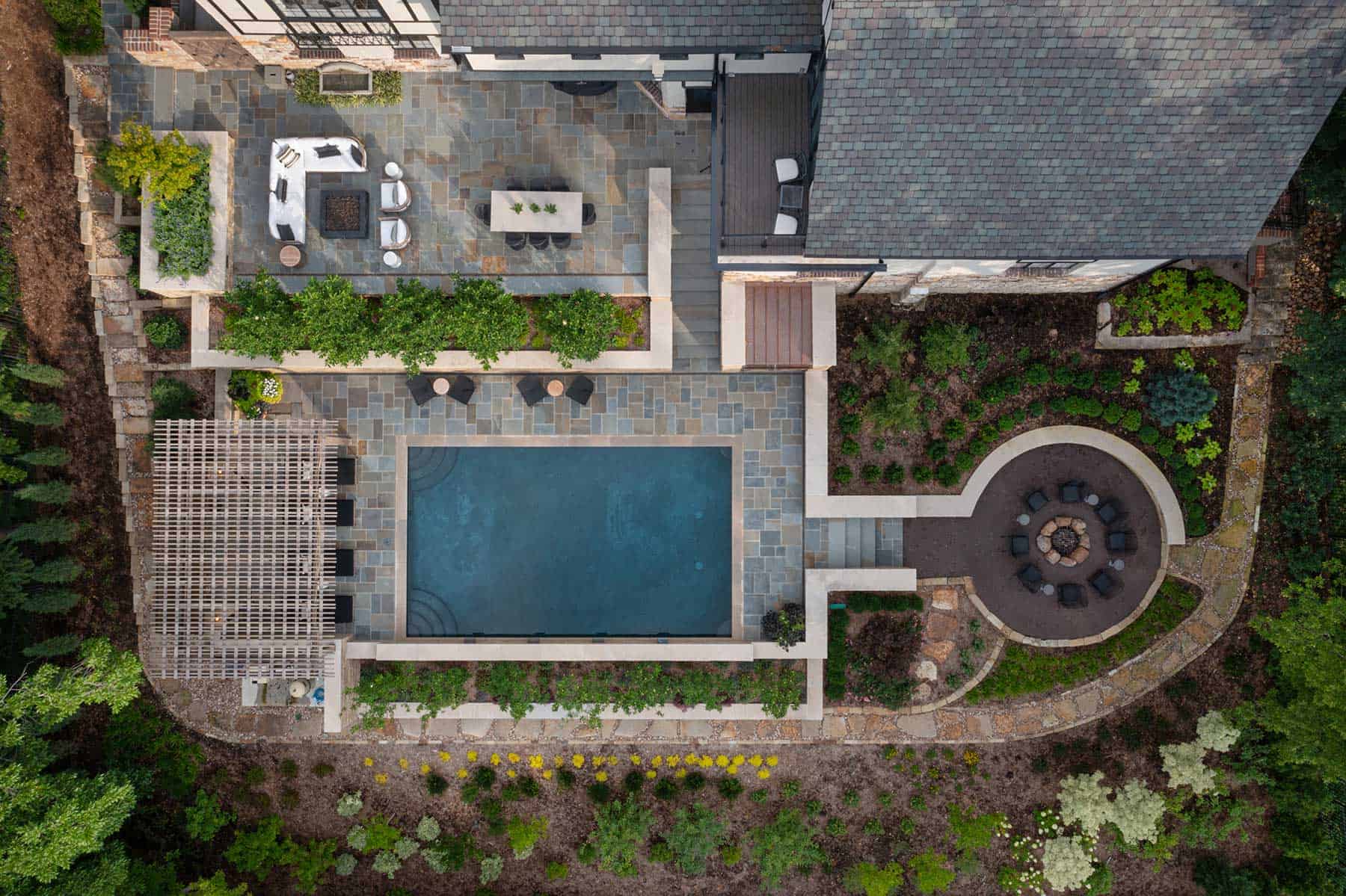 Aerial view of a Tudor house with a terraced pool and landscaped grounds behind it