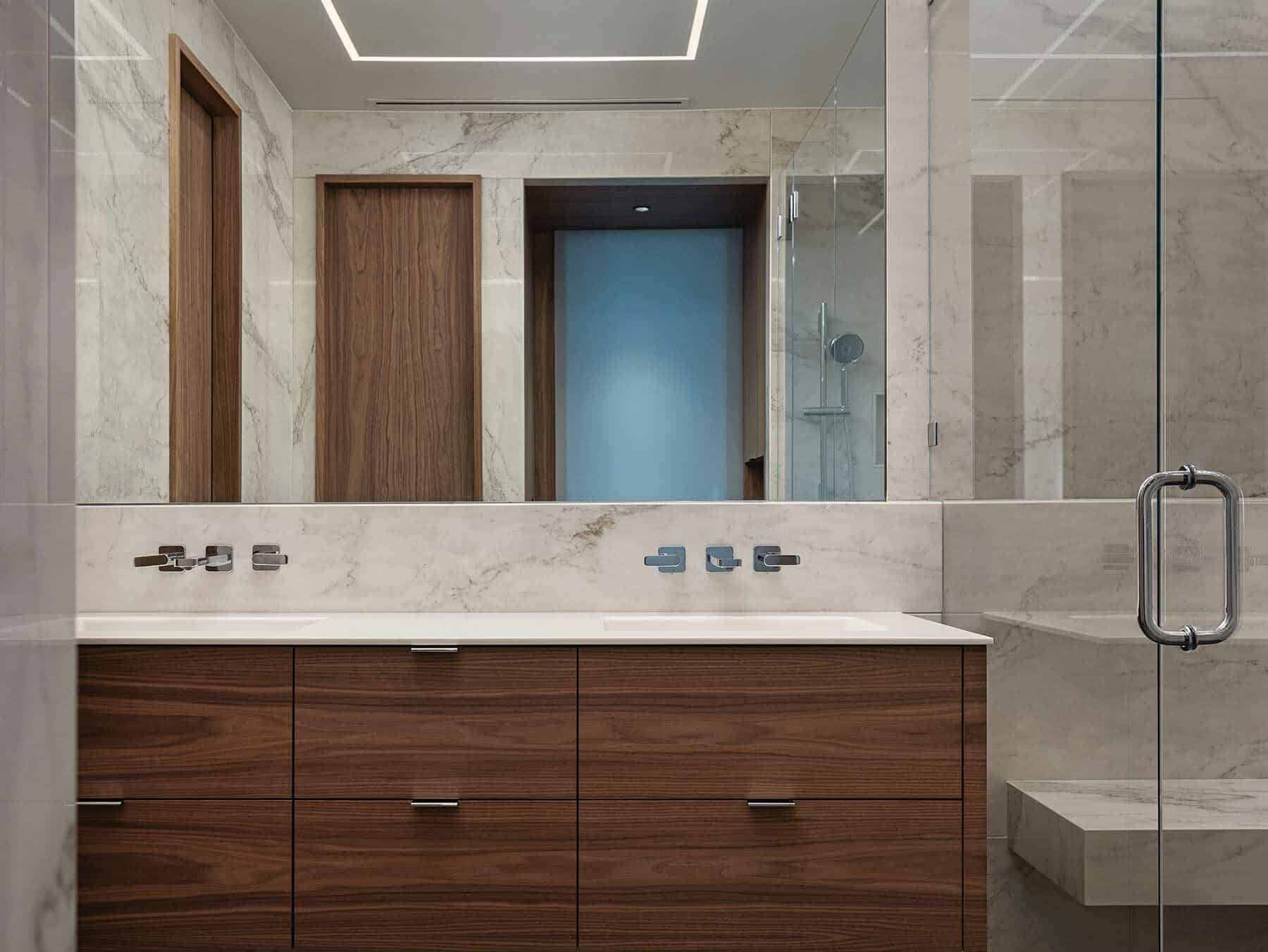 Bathroom with a floating walnut vanity, stone counter and a glass shower enclosure