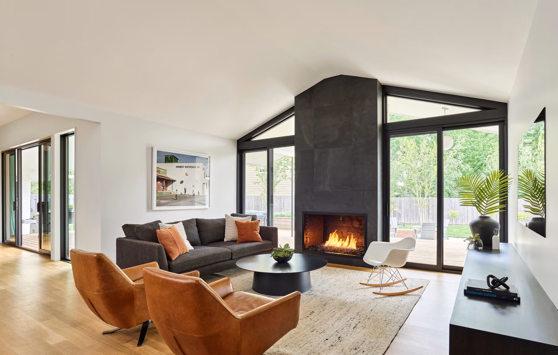 Modern living room with floor-to-ceiling glass and a blackened steel fireplace, built by Faust Construction