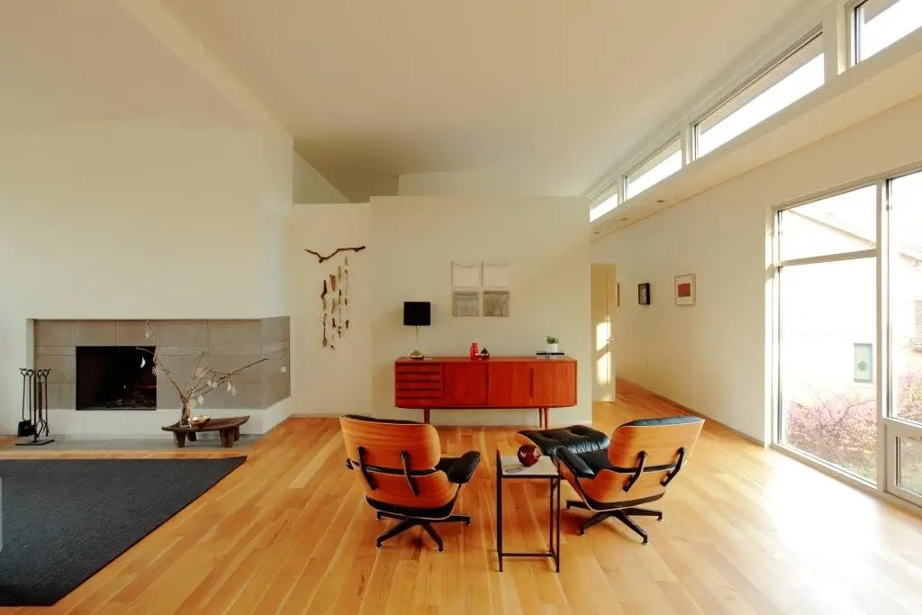Living area with two leather lounge chairs, a wood credenza, the fireplace at left and clerestory windows above