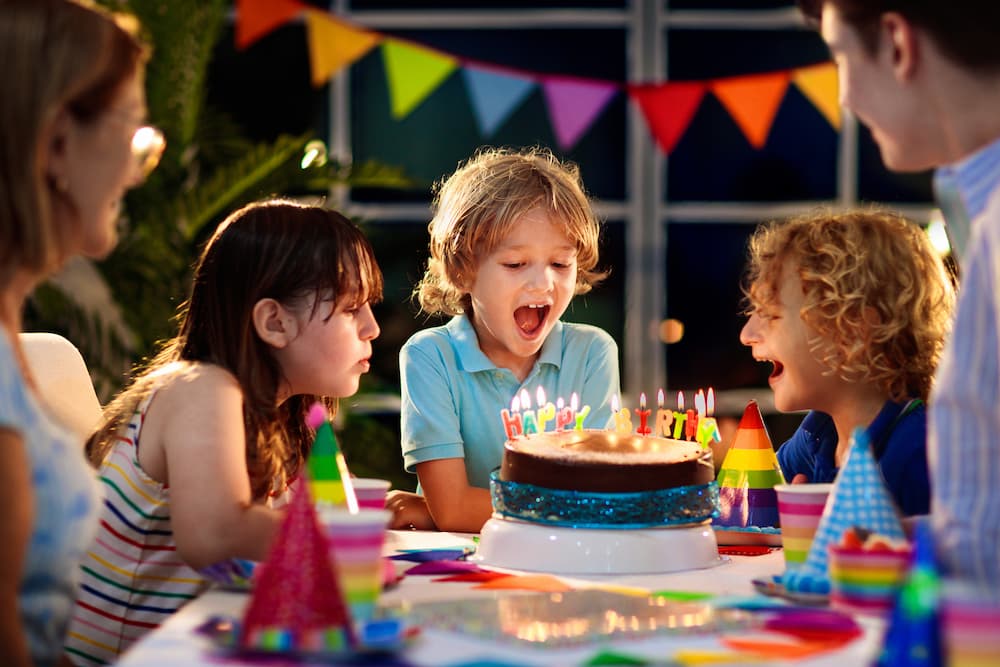 Children gathered around a birthday cake with candles at a Miami kids' birthday party, highlighting local family-friendly event venues and celebrations.