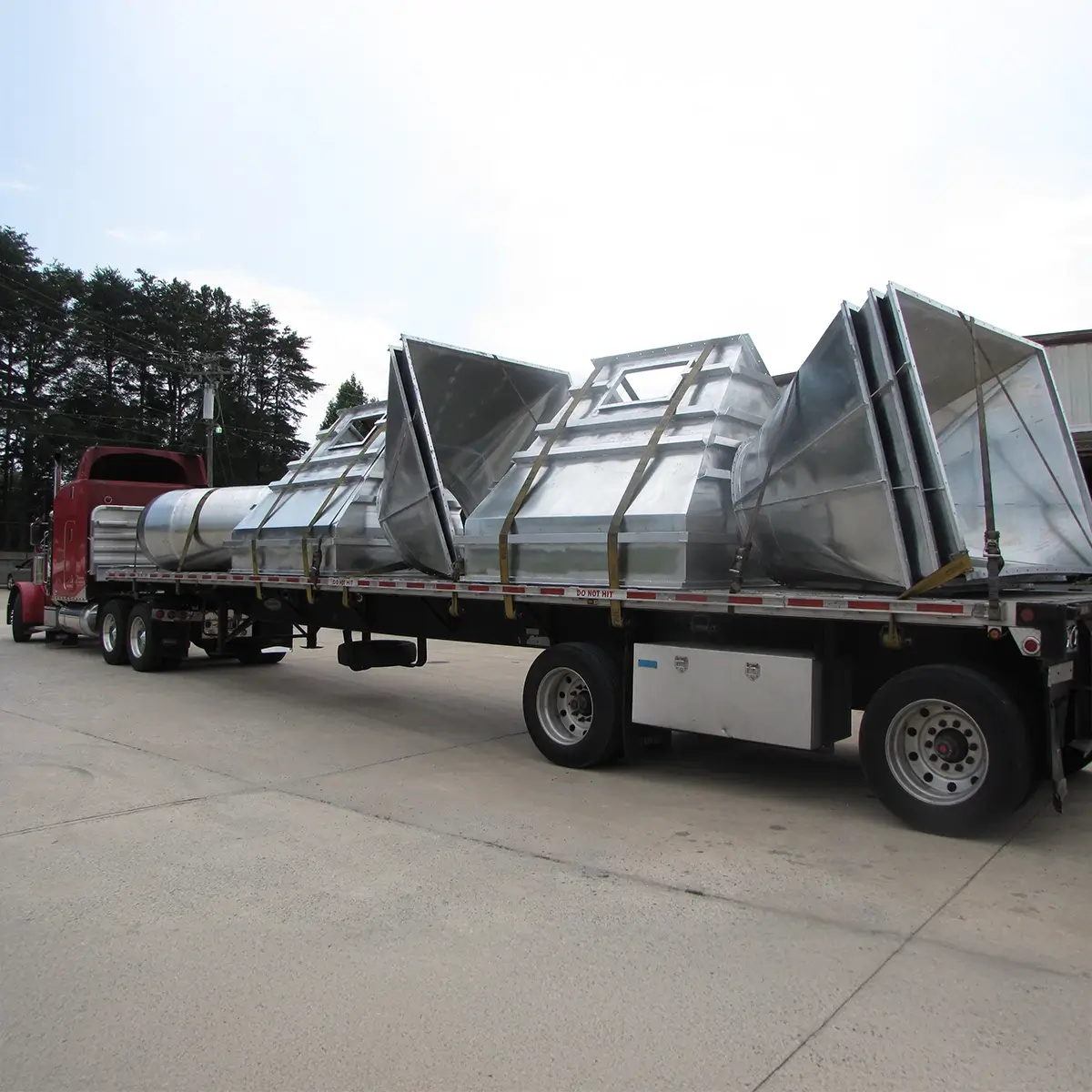 Tractor-trailer with load of large custom hoods.