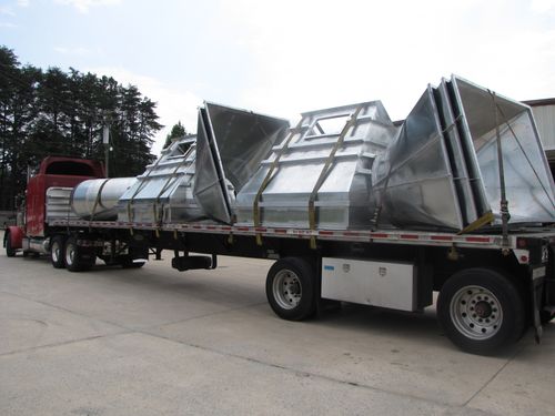 Tractor-trailer with load of large custom hoods.