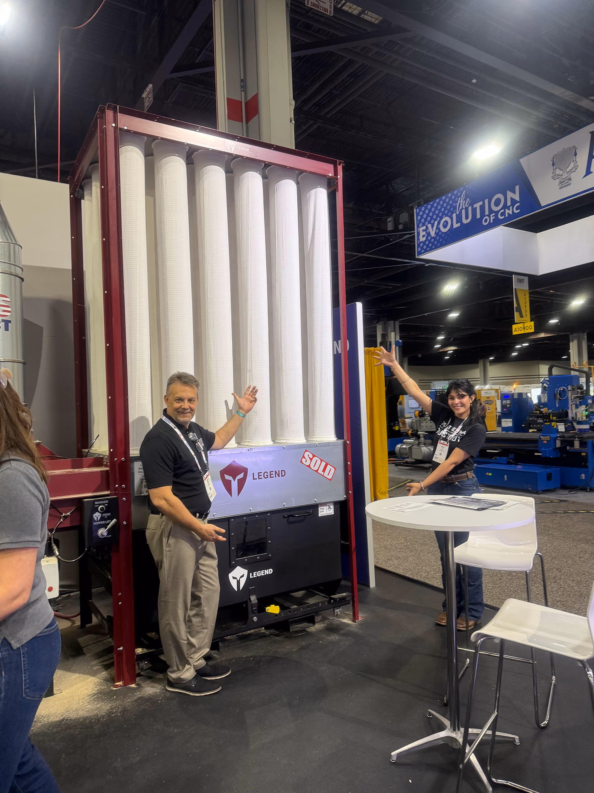 Two people presenting a large Legend industrial air filter unit marked sold at a trade show booth.