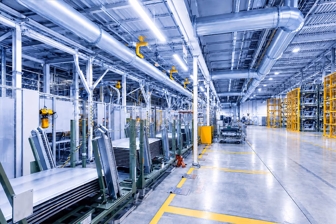 Stainless steel industrial tubing system with angled pipes and connected machinery in a factory setting.