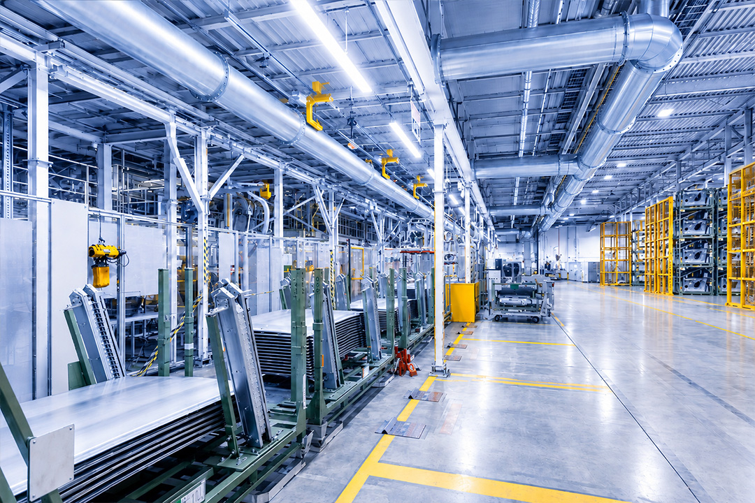 Stainless steel industrial tubing system with angled pipes and connected machinery in a factory setting.