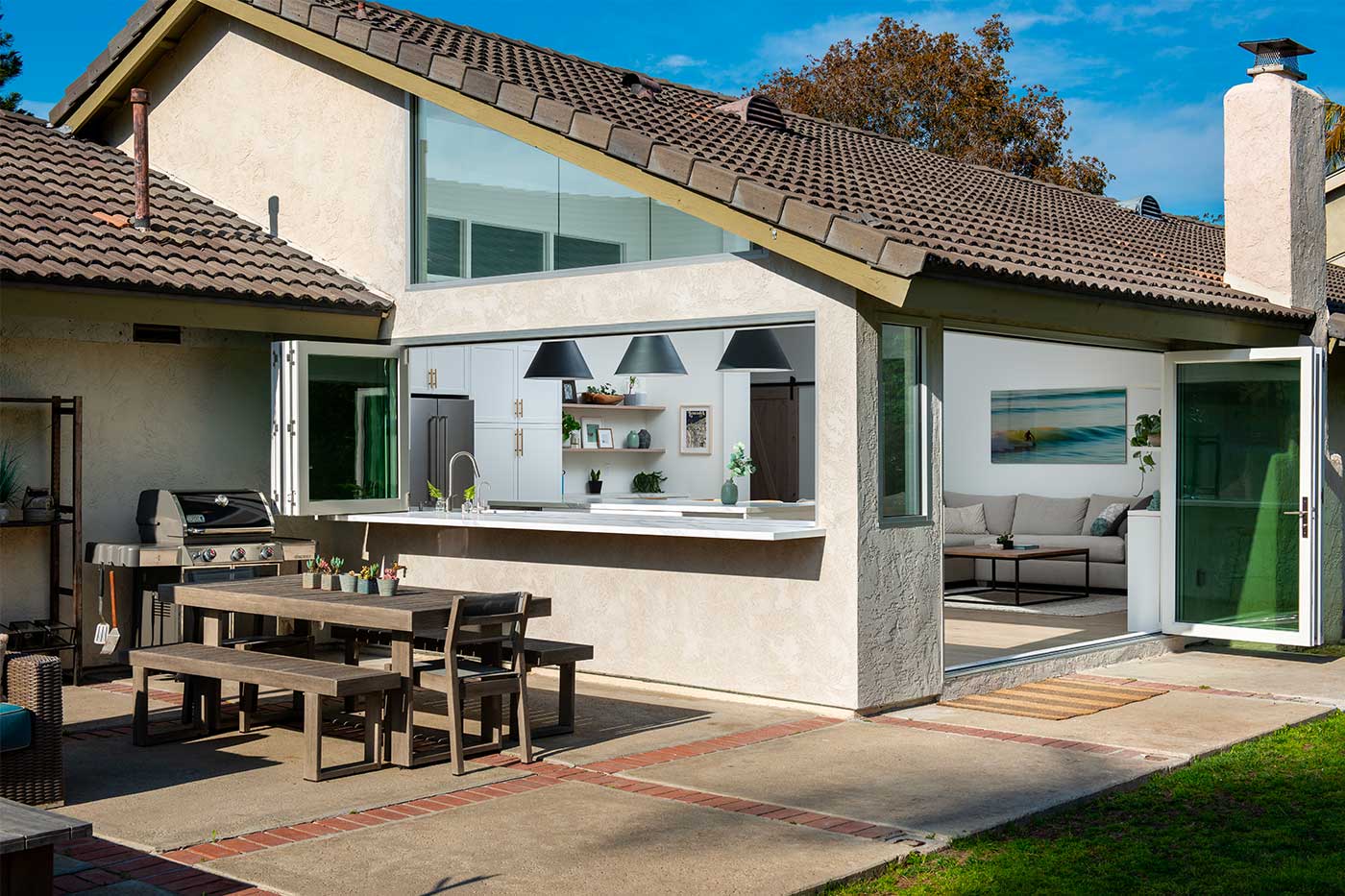 Large 4-panel bifold passthrough window in a modern farmhouse kitchen, replacing upper cabinets on an exterior wall. Outdoor patio visible. 