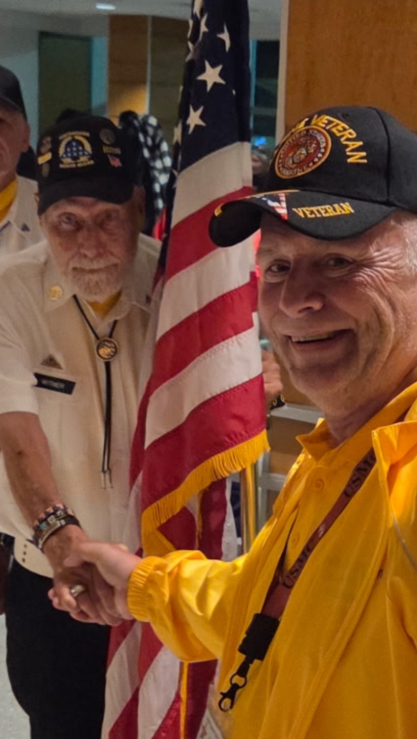 Image of two veterans shaking hands in front of an American flag.