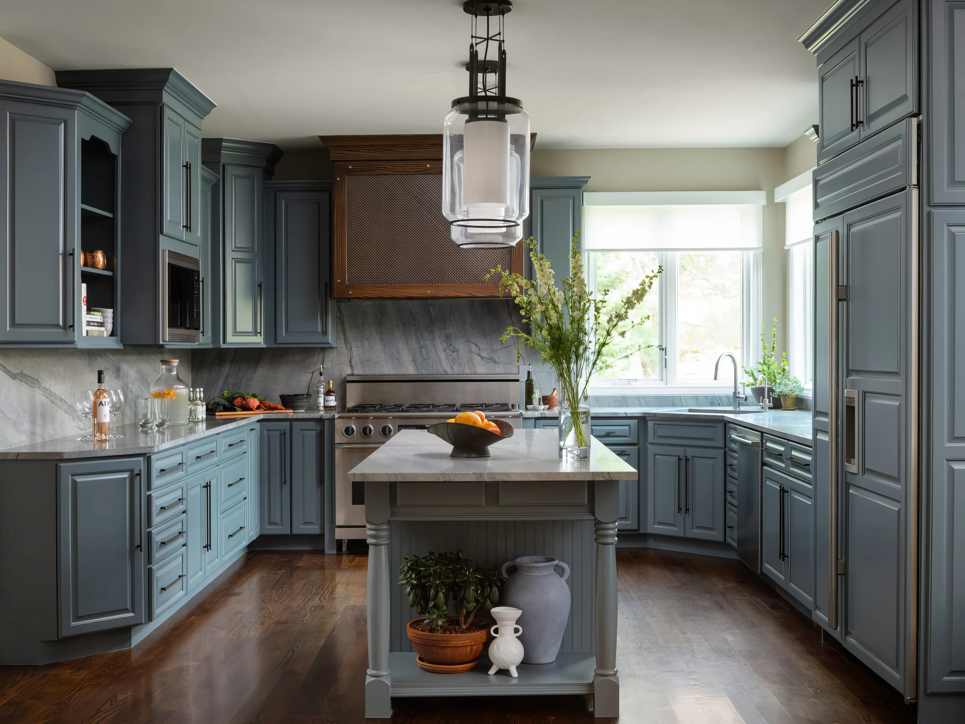 A newly remodeled kitchen with blue cabinets and marble accent walls that is warm and welcoming