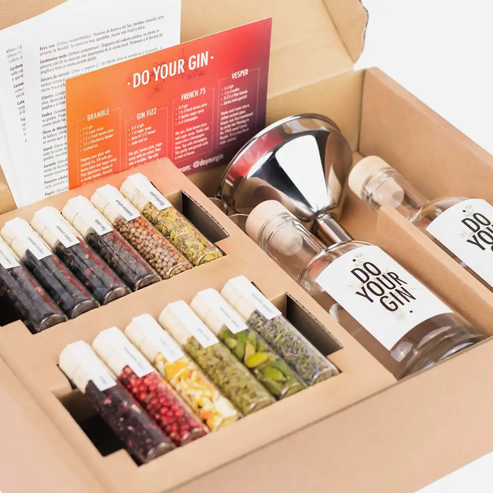DIY-Gin-Baukasten mit Botanicals in kleinen Glasröhrchen, zwei Flaschen und Trichter in einer Geschenkbox.