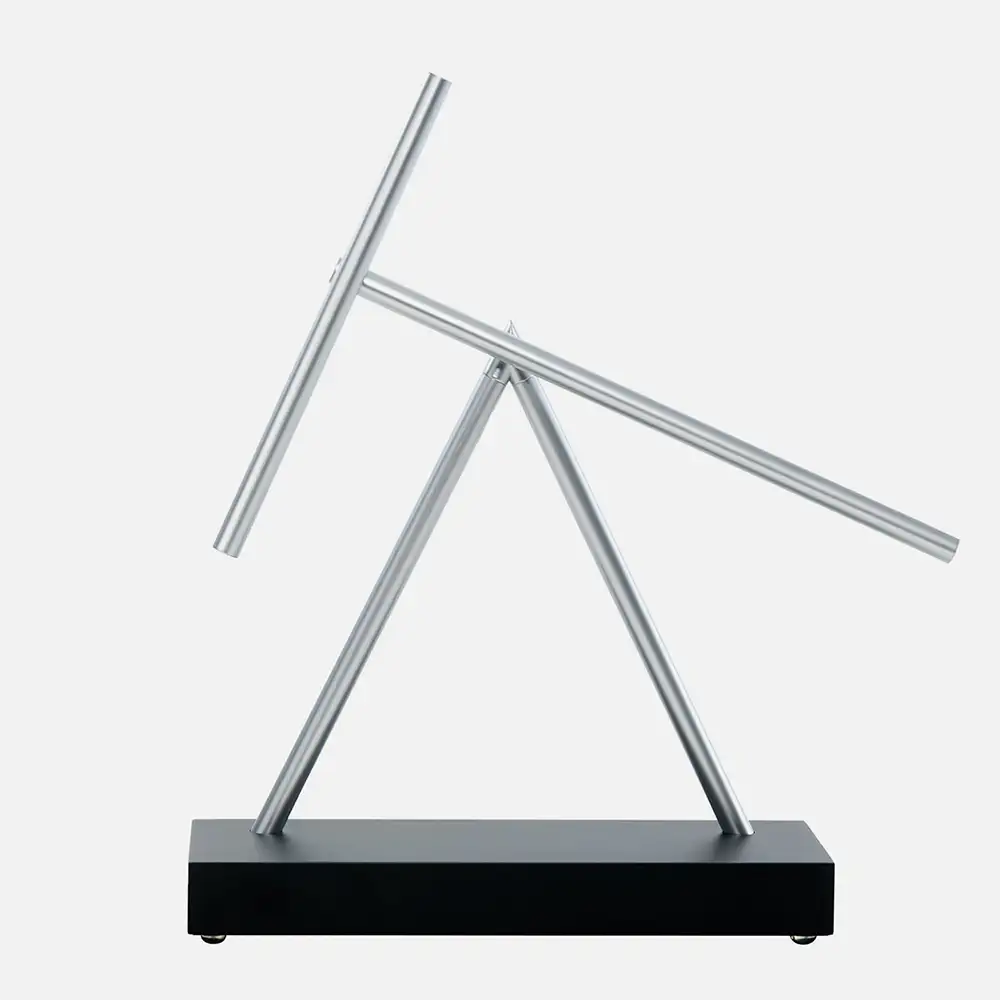 Swinging Sticks – kinetische Balance-Skulptur mit zwei pendelnden Stäben auf einem Schreibtisch.