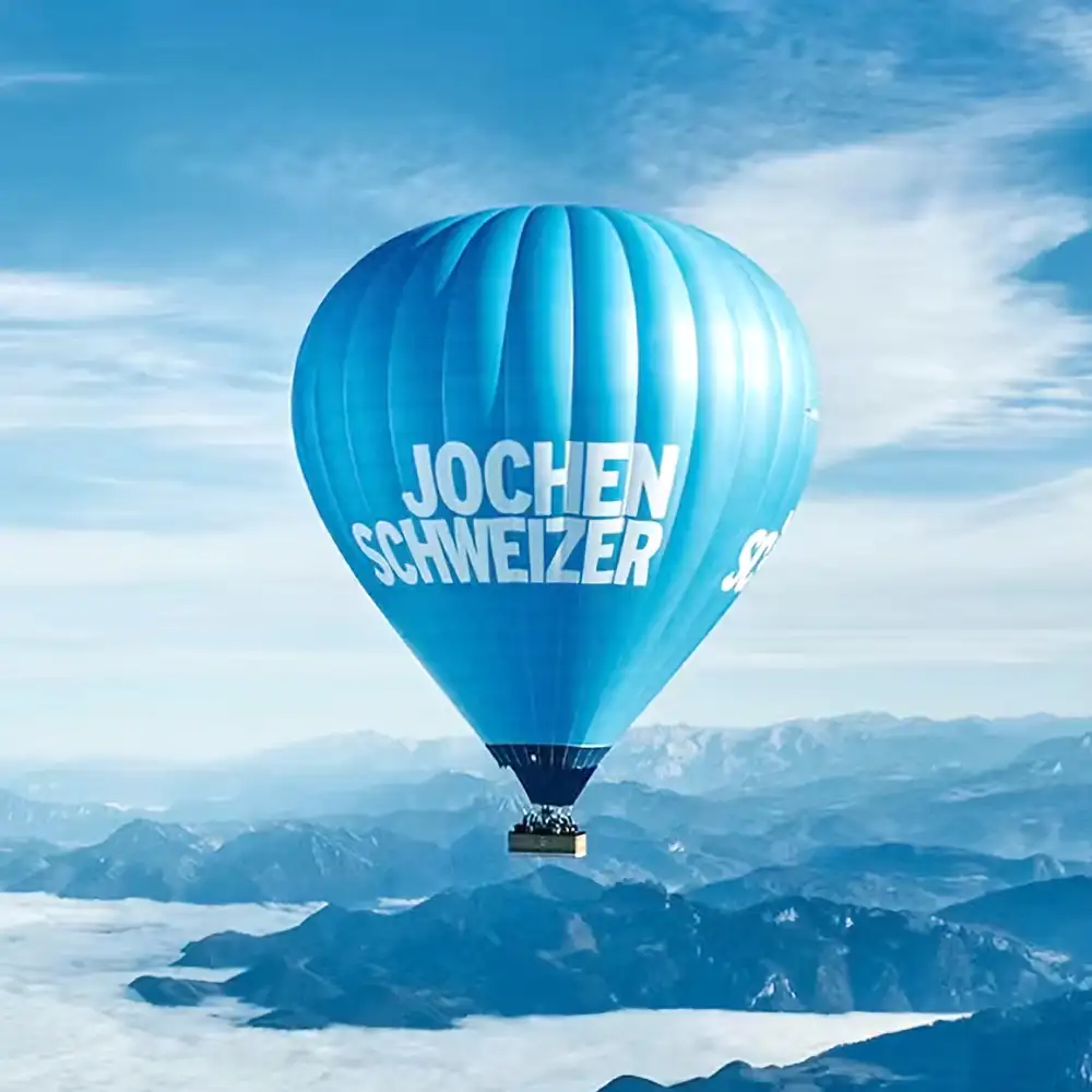 Heißluftballon in der Luft mit Panoramablick auf eine bergigen Landschaft bei klarem Himmel