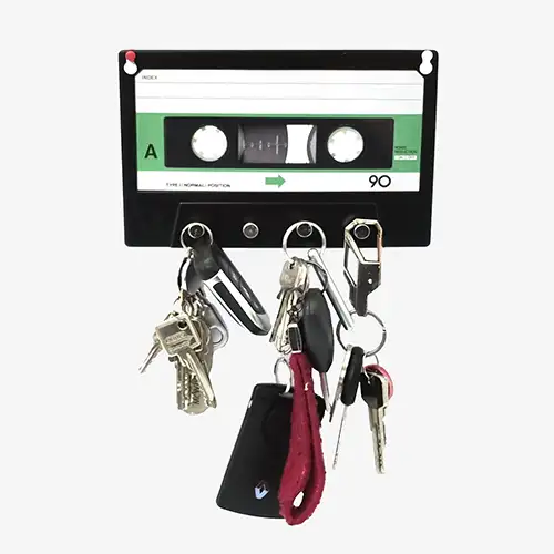Schlüsselbrett in Form einer Musikkassette aus Metall mit vier Haken, montiert an heller Wand