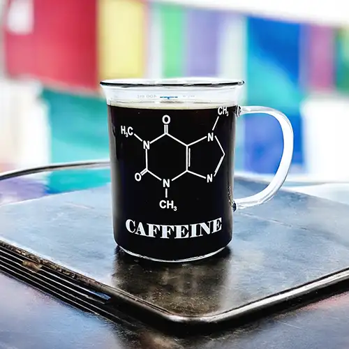 Durchsichtiges Kaffeeglas im Messbecher-Stil mit Skala und aufgedruckter Koffein-Molekülstruktur und Schriftzug Caffeine