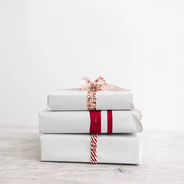 Drei weiß verpackte Geschenke übereinander gestapelt.