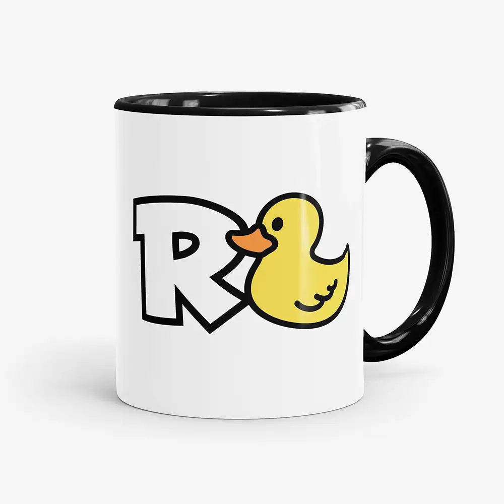 Weiße Kaffeetasse mit schwarzem Henkel und schwarzer Innenseite, bedruckt mit einem großen R und einer gelben Quietscheente als Wortspiel für „Rente“