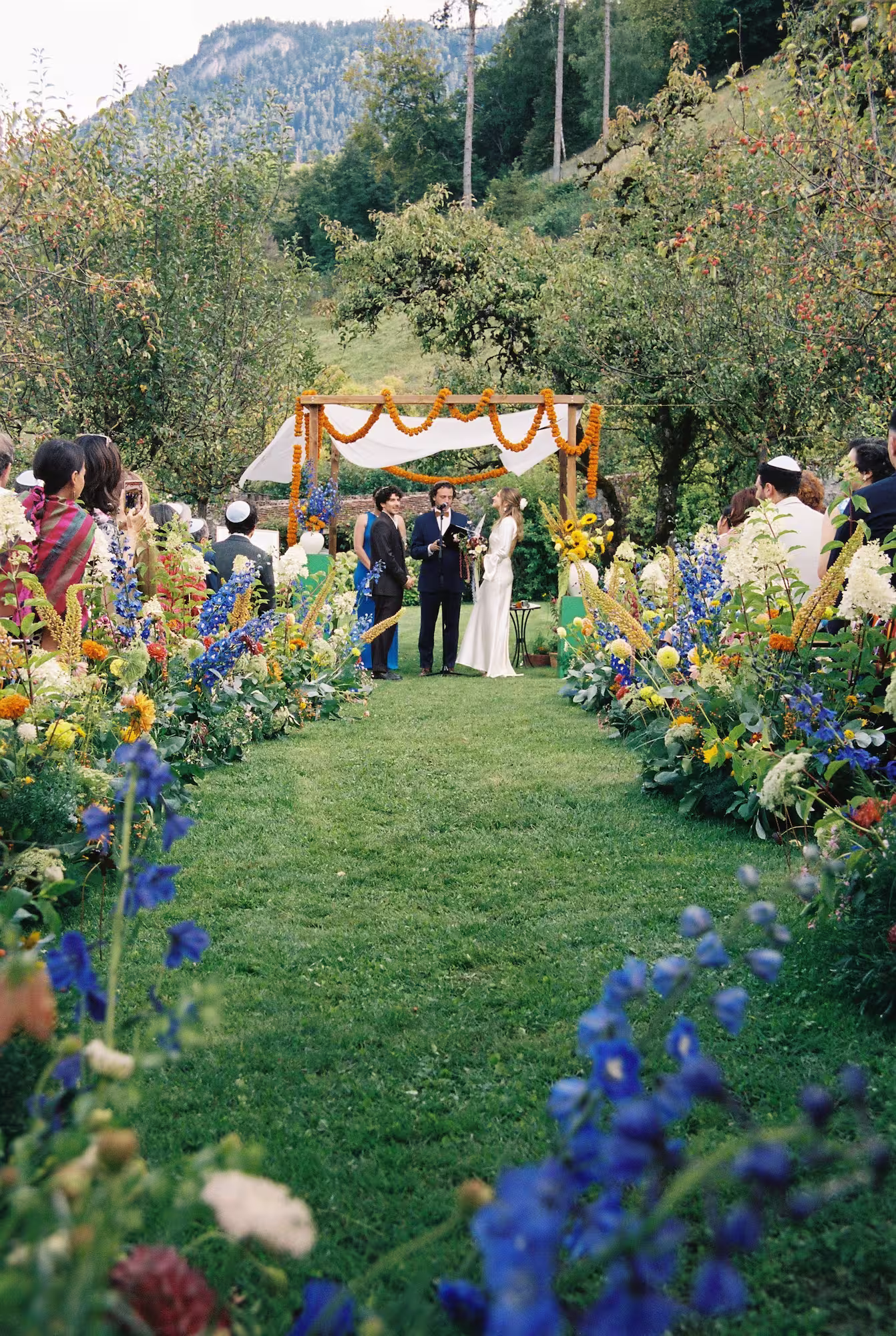 Cérémonie de mariage en extérieur sous une houppa fleurie à la Ferme de Gy, captée en argentique