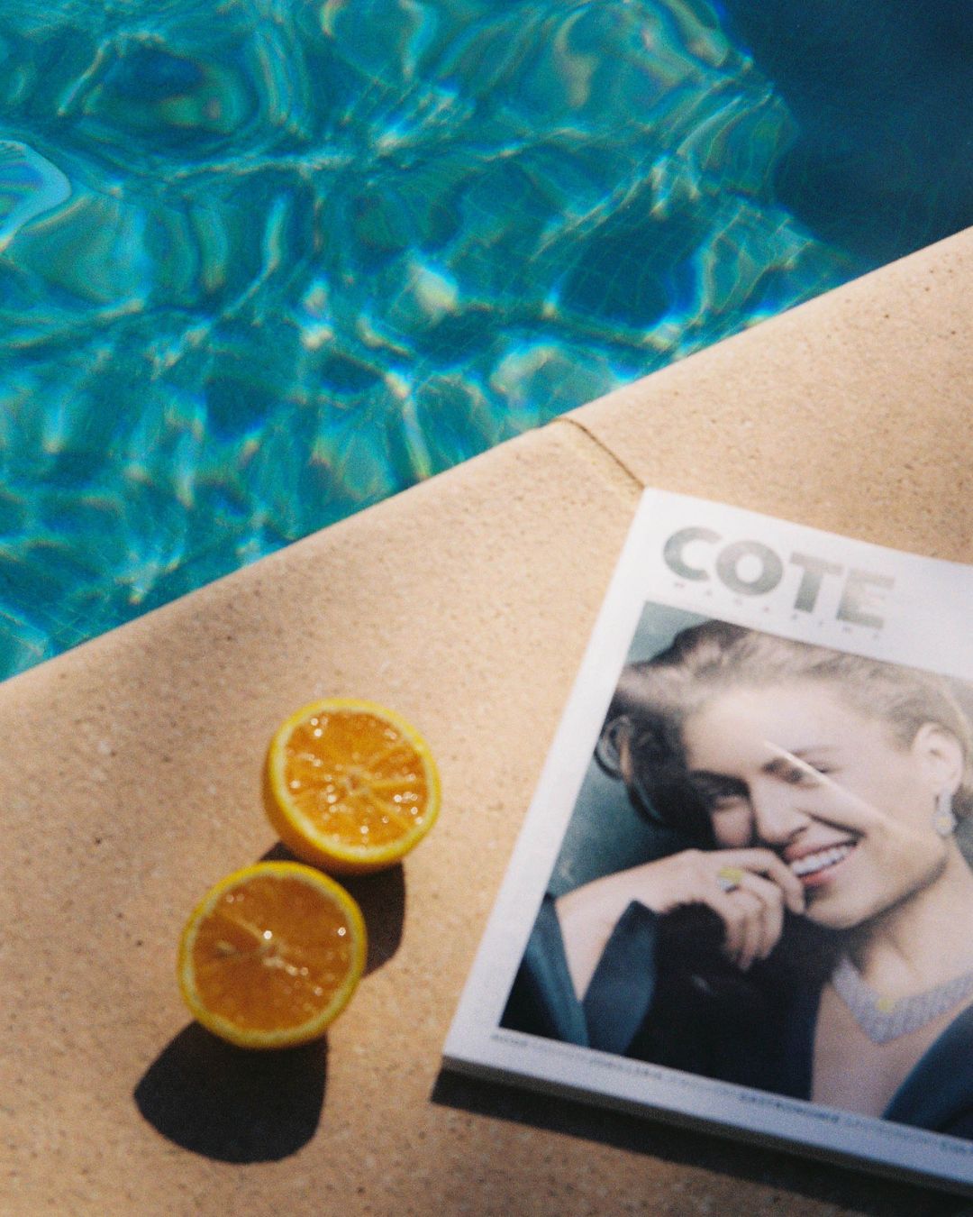 Magazine et oranges fraîches posés au bord de la piscine de l'hôtel le Catalogne, sous le soleil de Saint-Aygulf.
