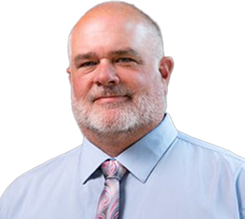 Middle-aged man with a bald head and gray beard wearing a light blue shirt and patterned tie, smiling slightly against a gray background.